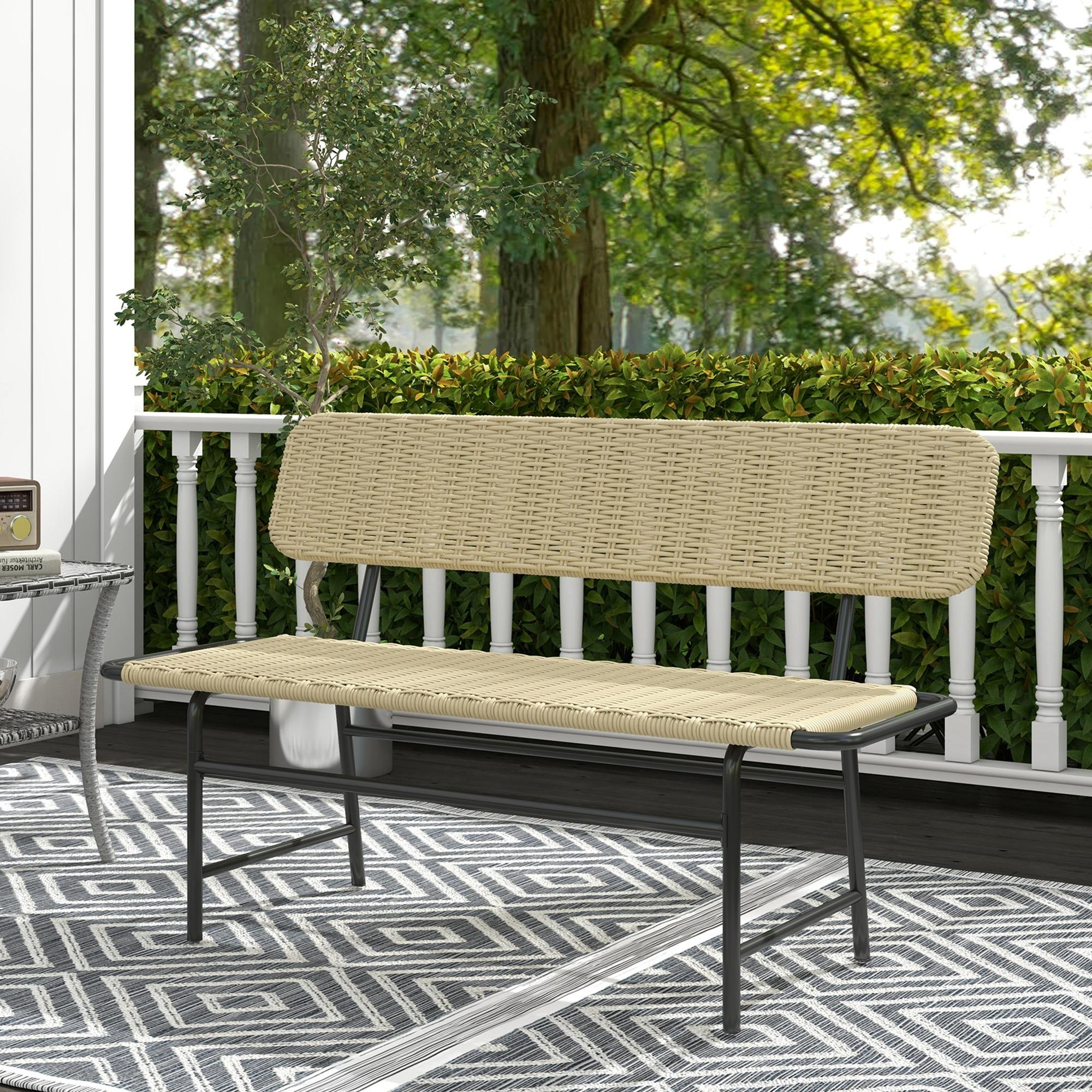 Eine beige geflochtene Bank mit schwarzem Metallrahmen steht auf einer Terrasse mit einem gemusterten Teppich im Freien.