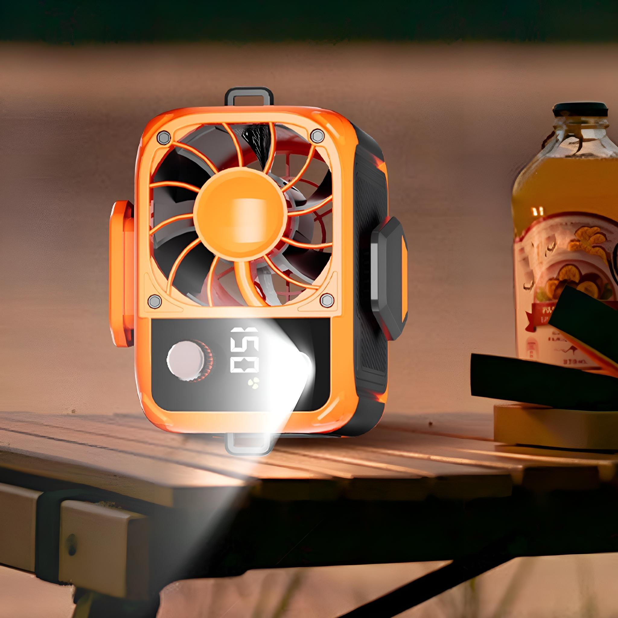 Orangener tragbarer Ventilator auf einem Holztisch neben einer Flasche Saft.