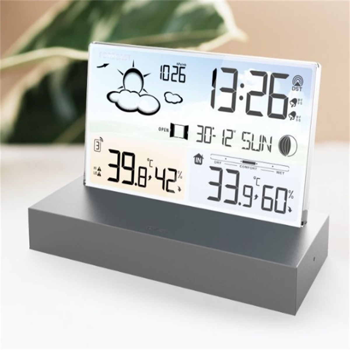 Eine Wetterstation auf einem grauen Ständer, die Innen-/Außentemperaturen, Luftfeuchtigkeit, Uhrzeit, Datum und Wettervorhersage anzeigt.
