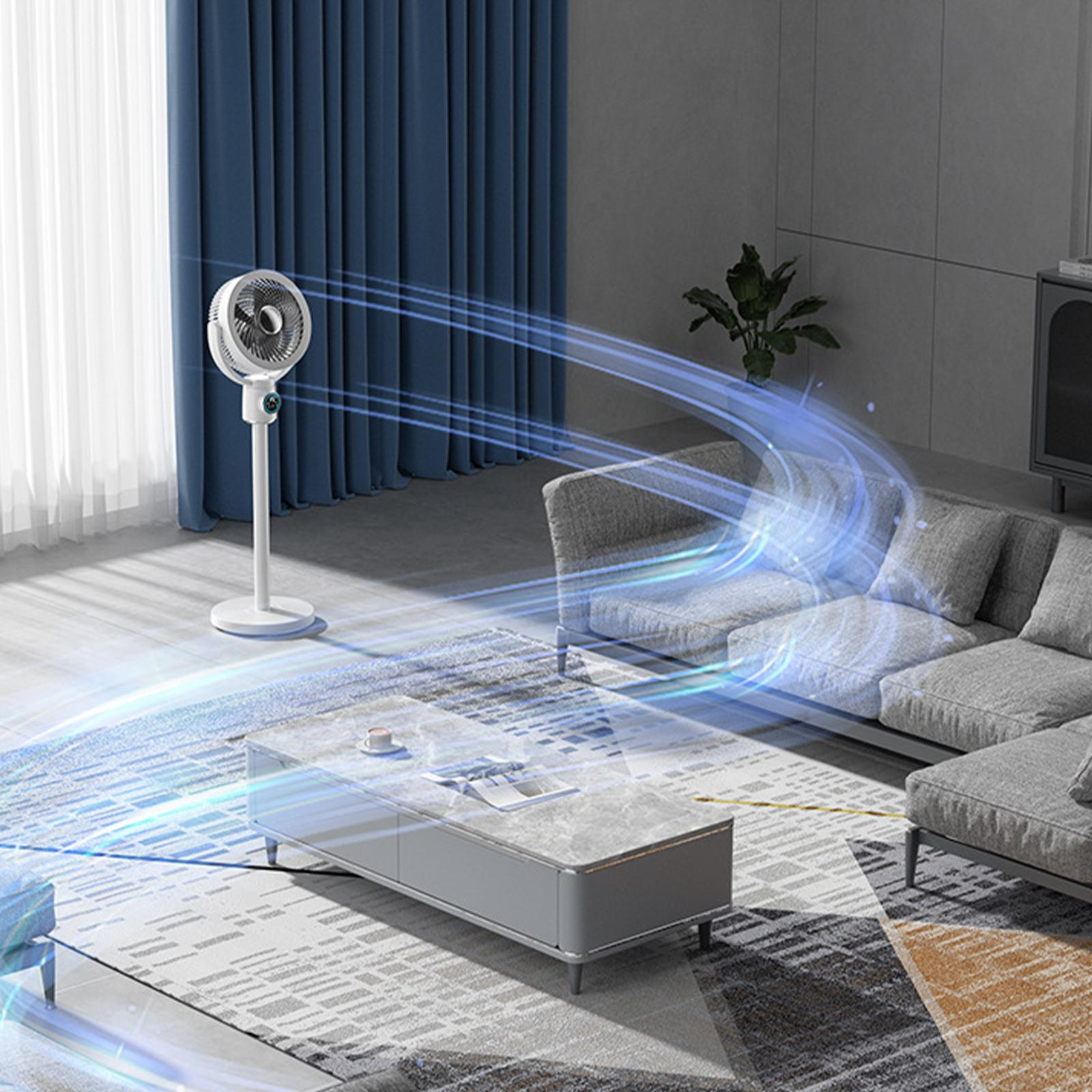 Wohnzimmeraufbau mit einem weißen Standventilator, der Luft zirkuliert, Sofa, Tisch und Vorhängen.