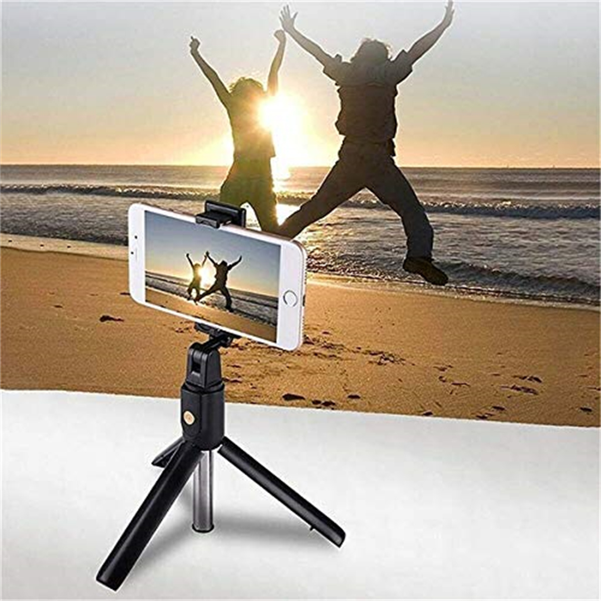 Ein Telefon auf einem Stativ fängt zwei Personen ein, die bei Sonnenuntergang an einem Strand springen.