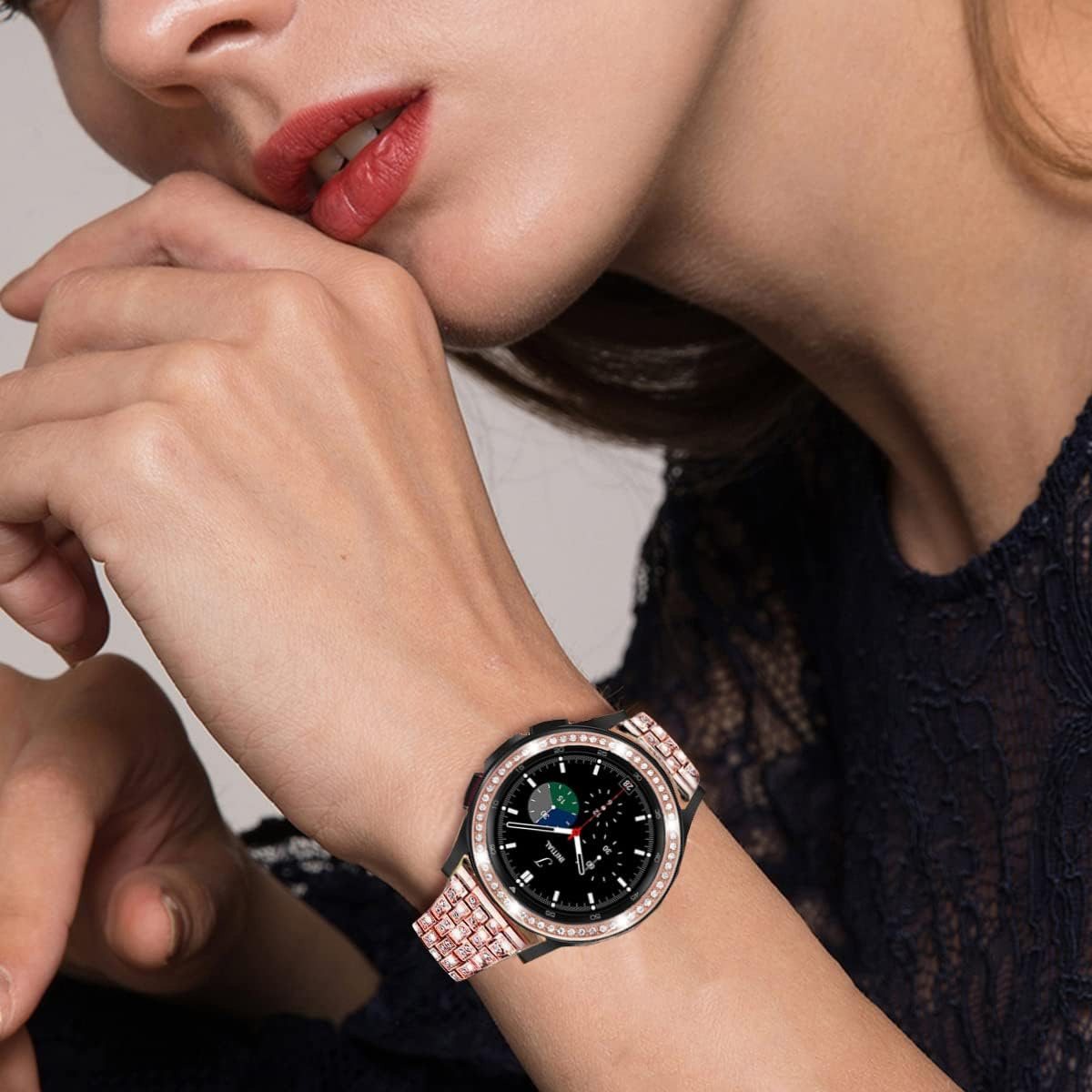 Eine Frau trägt eine schwarz-roségoldene Uhr am Handgelenk, dazu ein schwarzes Spitzentop.