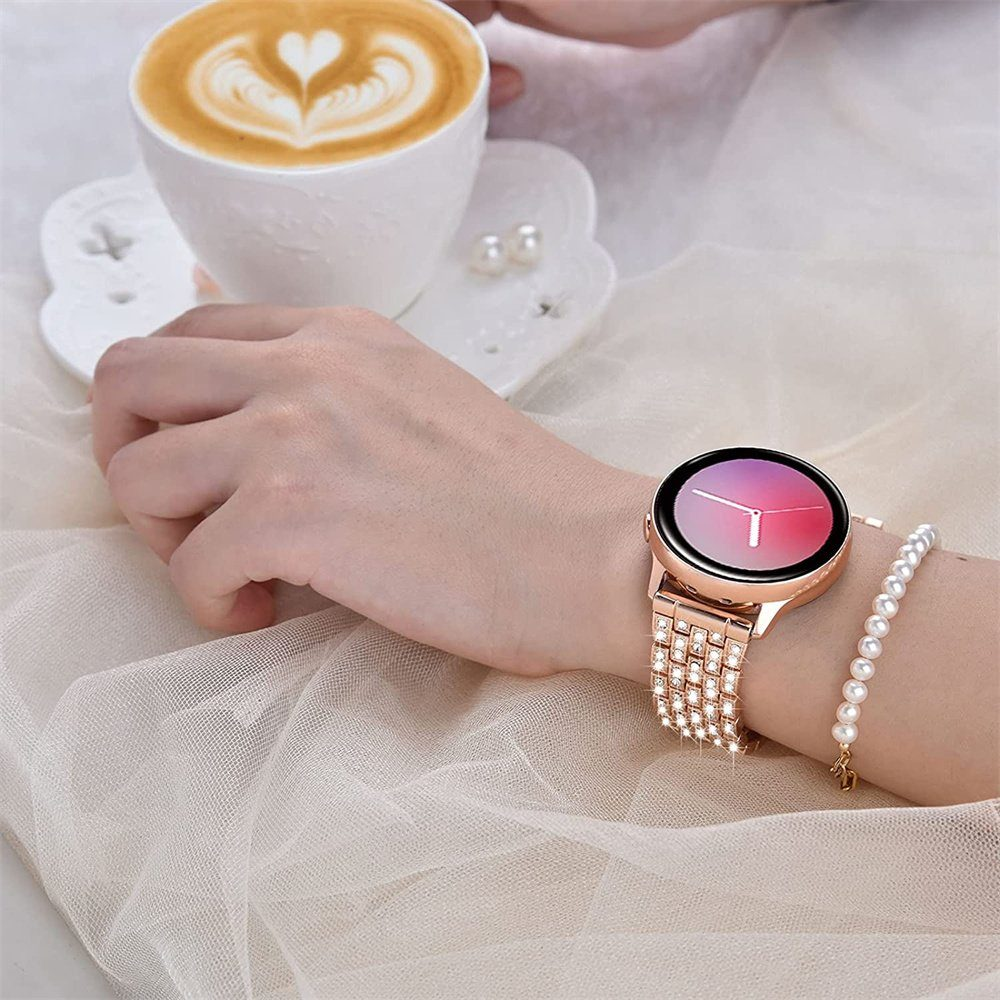 Das Handgelenk einer Frau mit einer roségoldenen Schmuckuhr und einem Perlenarmband neben einer Tasse Kaffee.