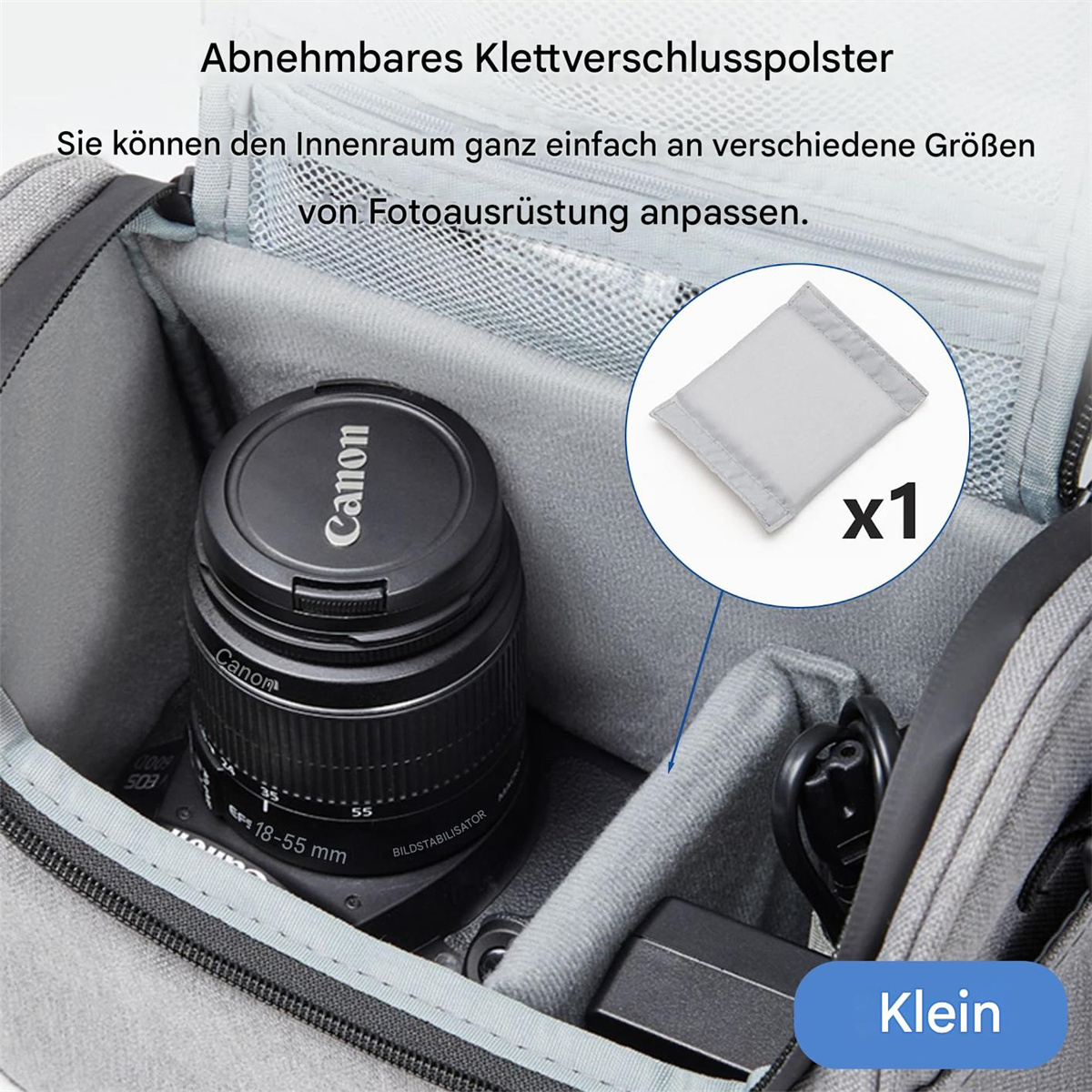 Offene graue Kameratasche mit Objektiv, herausnehmbarem Klettverschluss und kleinem schwarzen Netzteil.