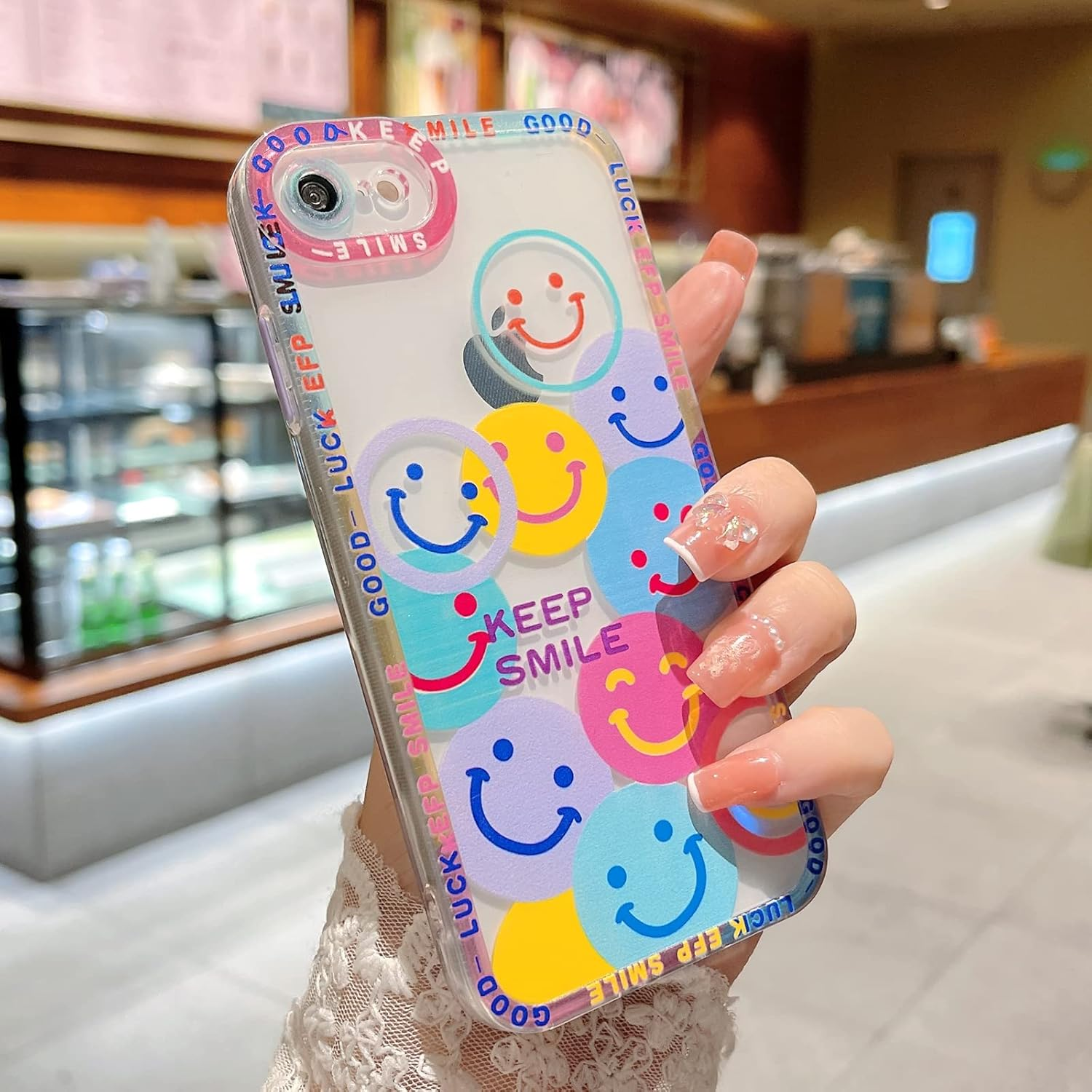 Eine Hand hält eine durchsichtige Handyhülle mit bunten Smileys und den Worten 'Keep Smile' und 'Luck EFP Smile'.