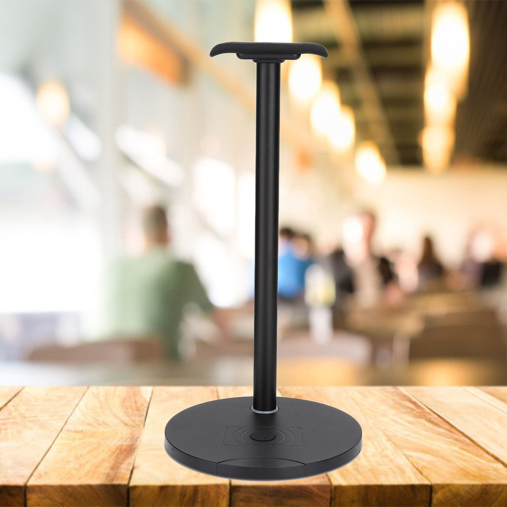 Schwarzer Kopfhörerständer auf einem Holztisch. Verschwommener Hintergrund eines Cafés.
