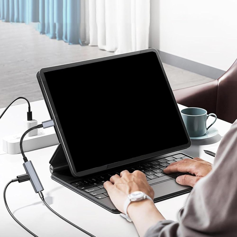 Eine Person benutzt ein Tablet, das mit einem Hub verbunden ist, während sie auf einer Tastatur tippt.