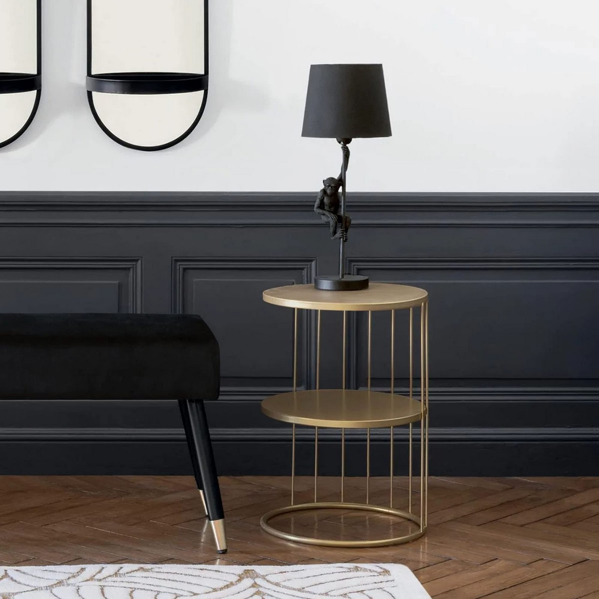 Una sala de estar con una mesa auxiliar dorada, lámpara, silla y decoración de pared.