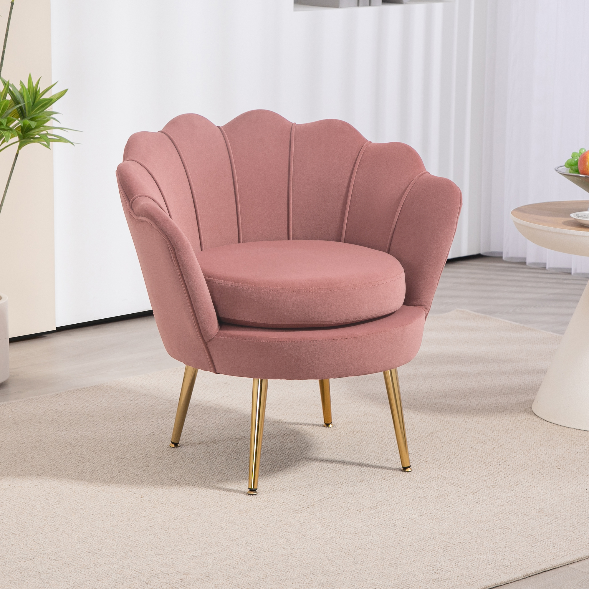 Silla de concha de terciopelo rosa con patas doradas en una sala de estar.