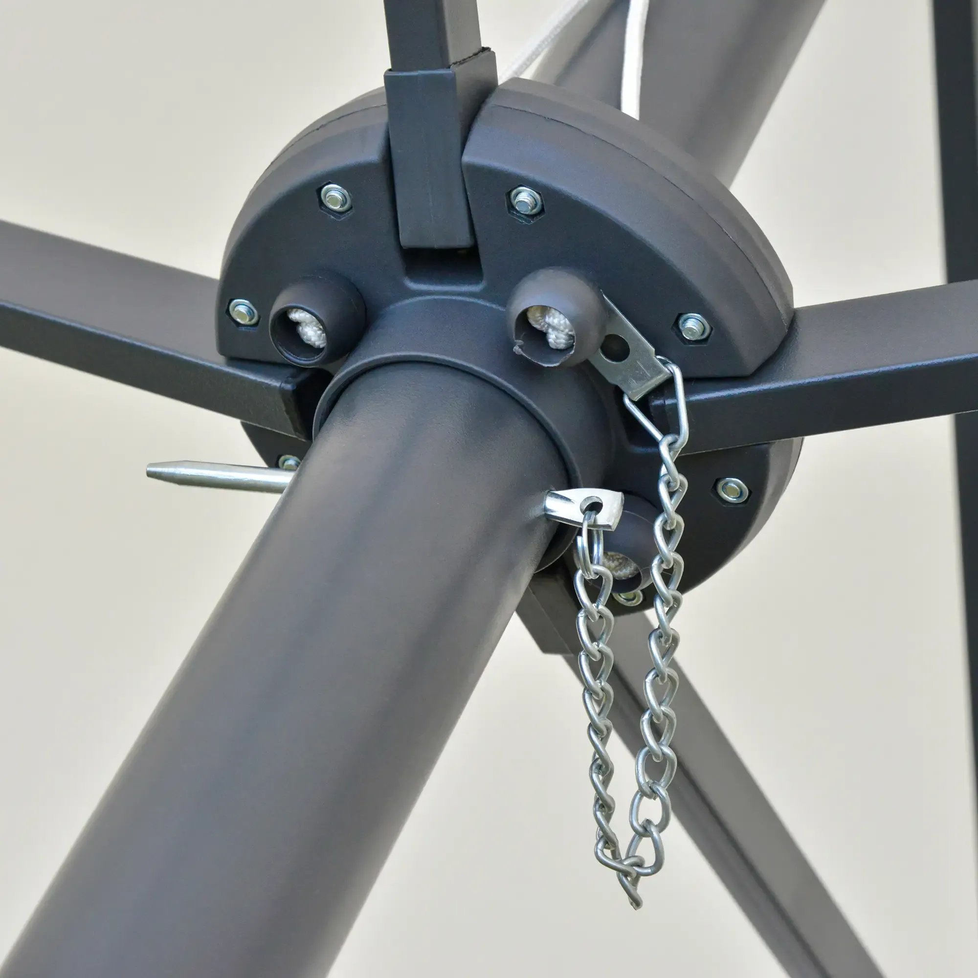 Eine Nahaufnahme zeigt ein schwarzes Metallgestell und Kettendetails eines Terrassenschirms.
