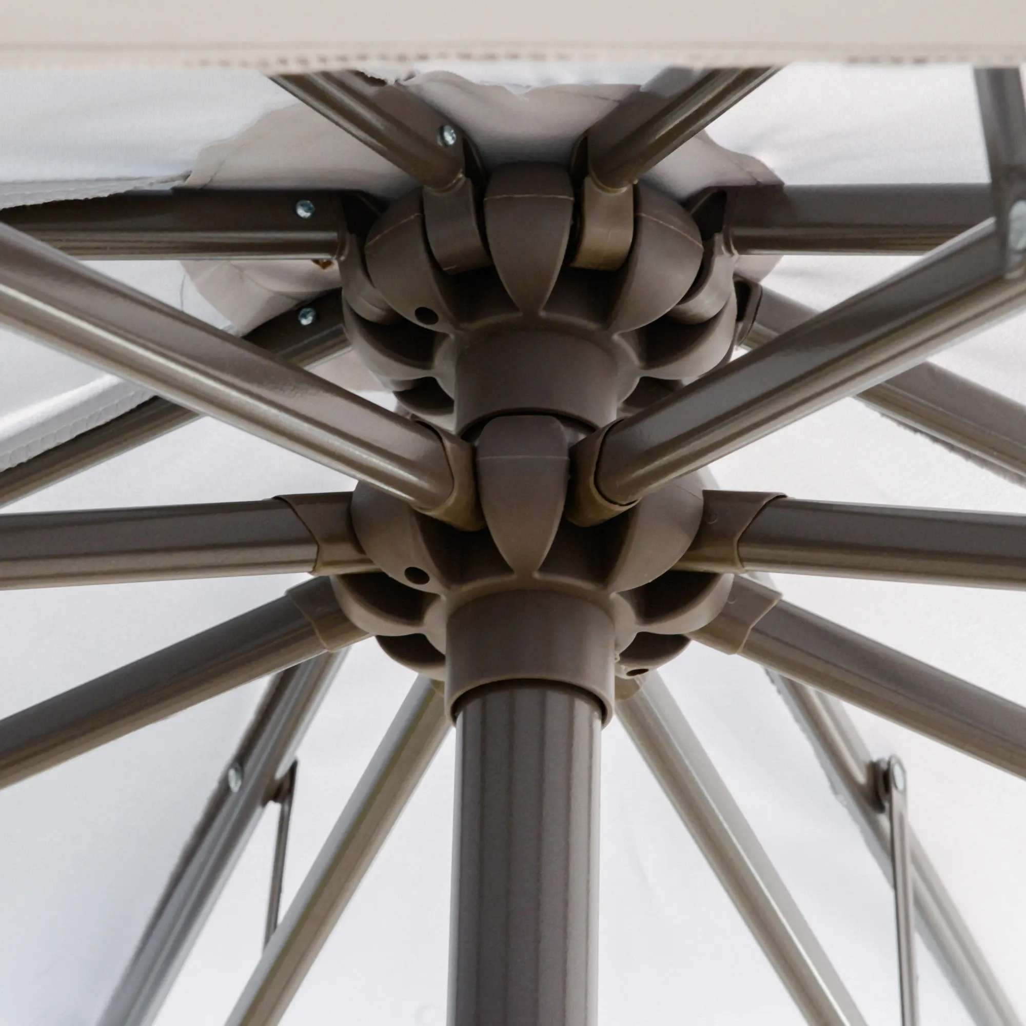 Nahaufnahme der Stützstruktur des Sonnenschirms mit braunen Metallstangen und zentralem Gelenk.