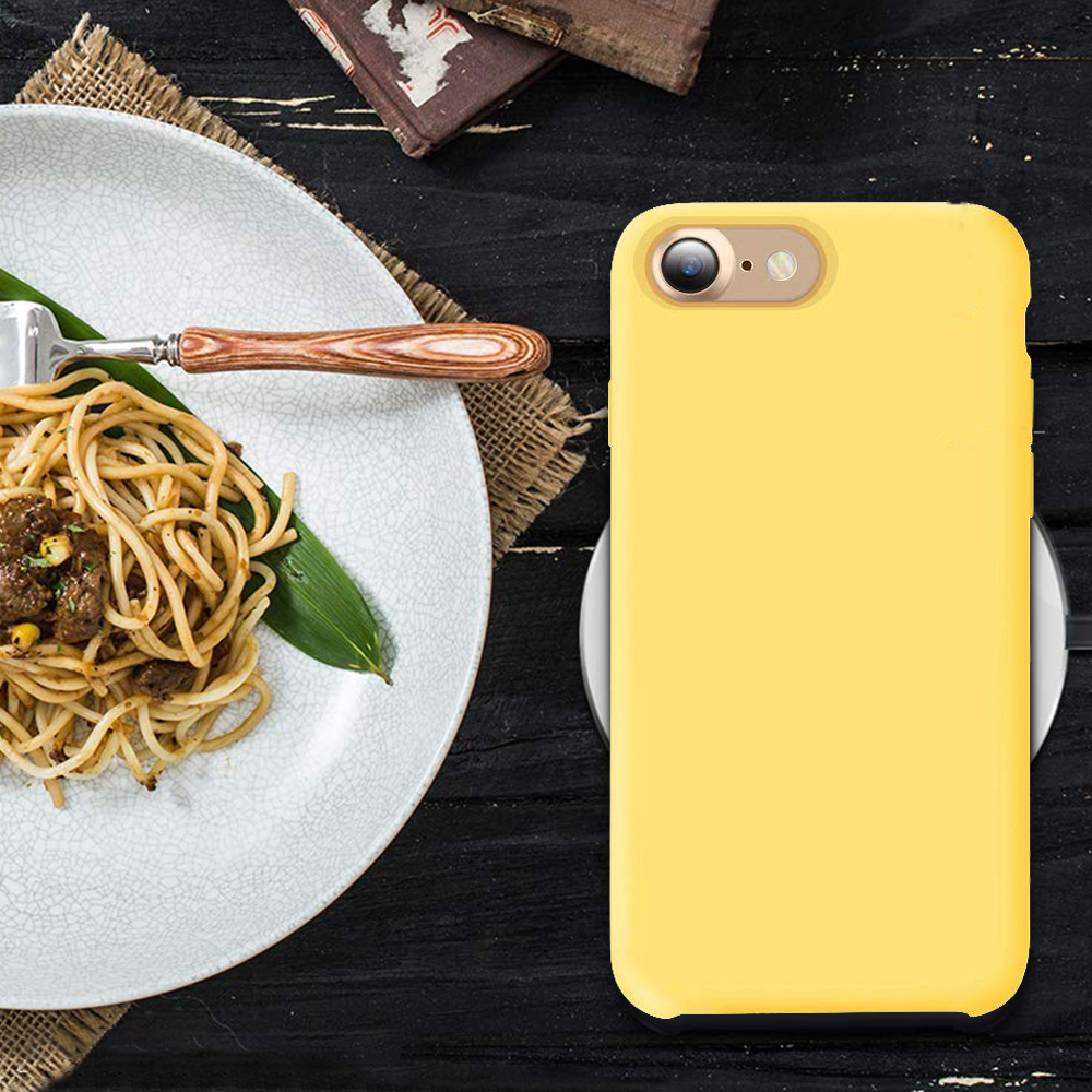 Ein Teller mit Spaghetti und eine gelbe Handyhülle auf einem schwarzen Tisch.