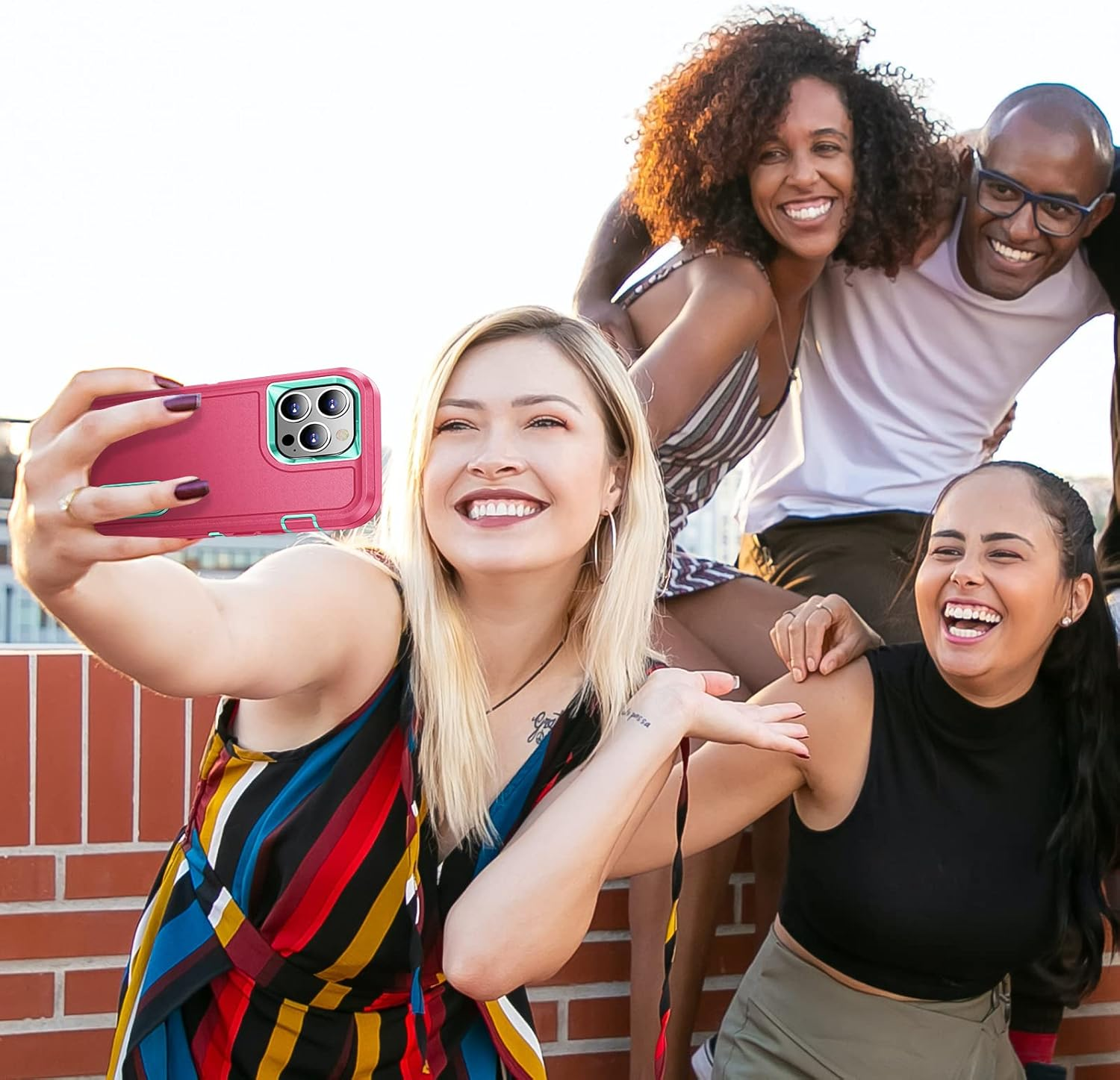 Eine Gruppe von vier Personen macht ein Selfie mit einer rosa und türkisfarbenen Handyhülle.