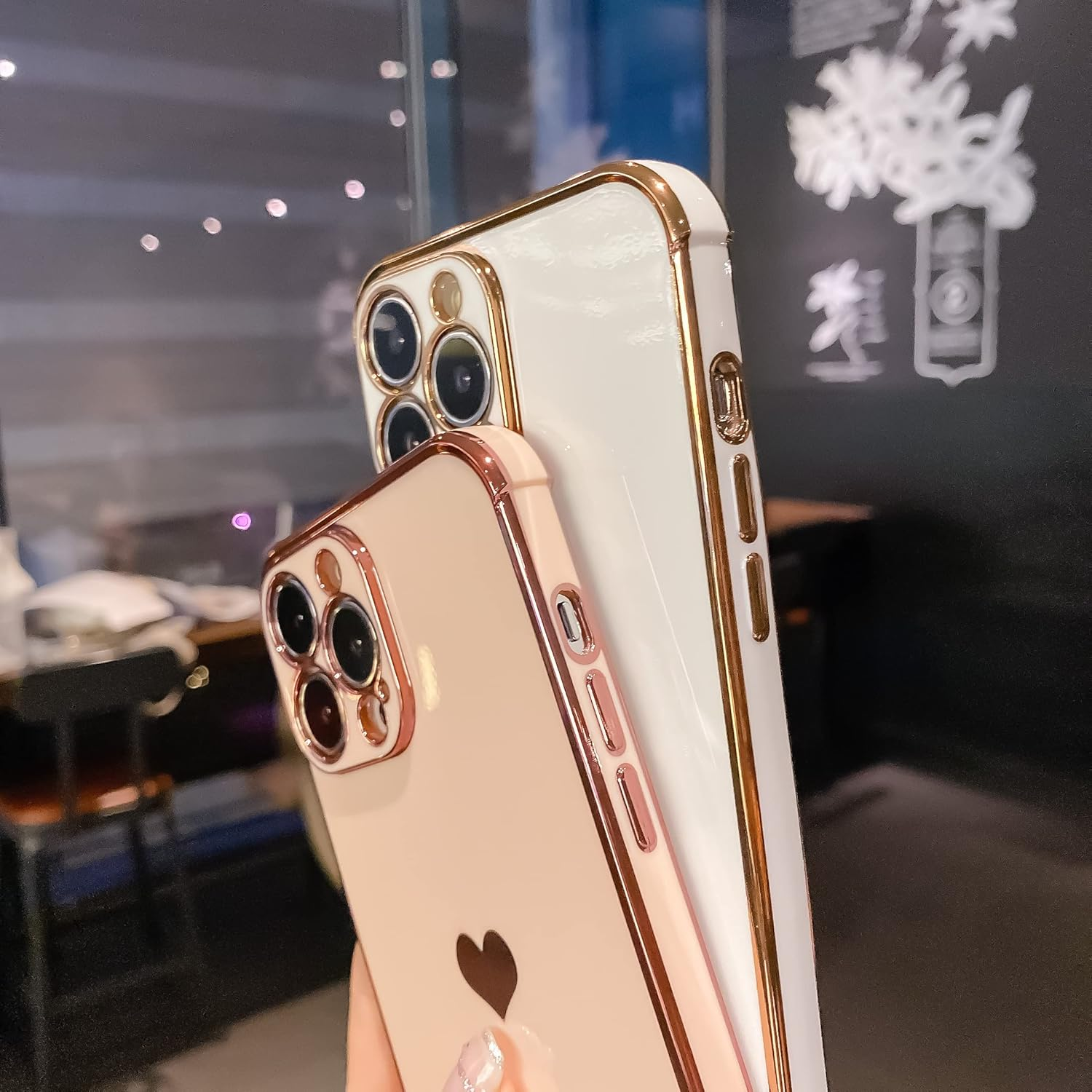Zwei iPhones mit goldenen Verzierungen und Herzmotiven. Eines ist weiß und das andere hellrosa.