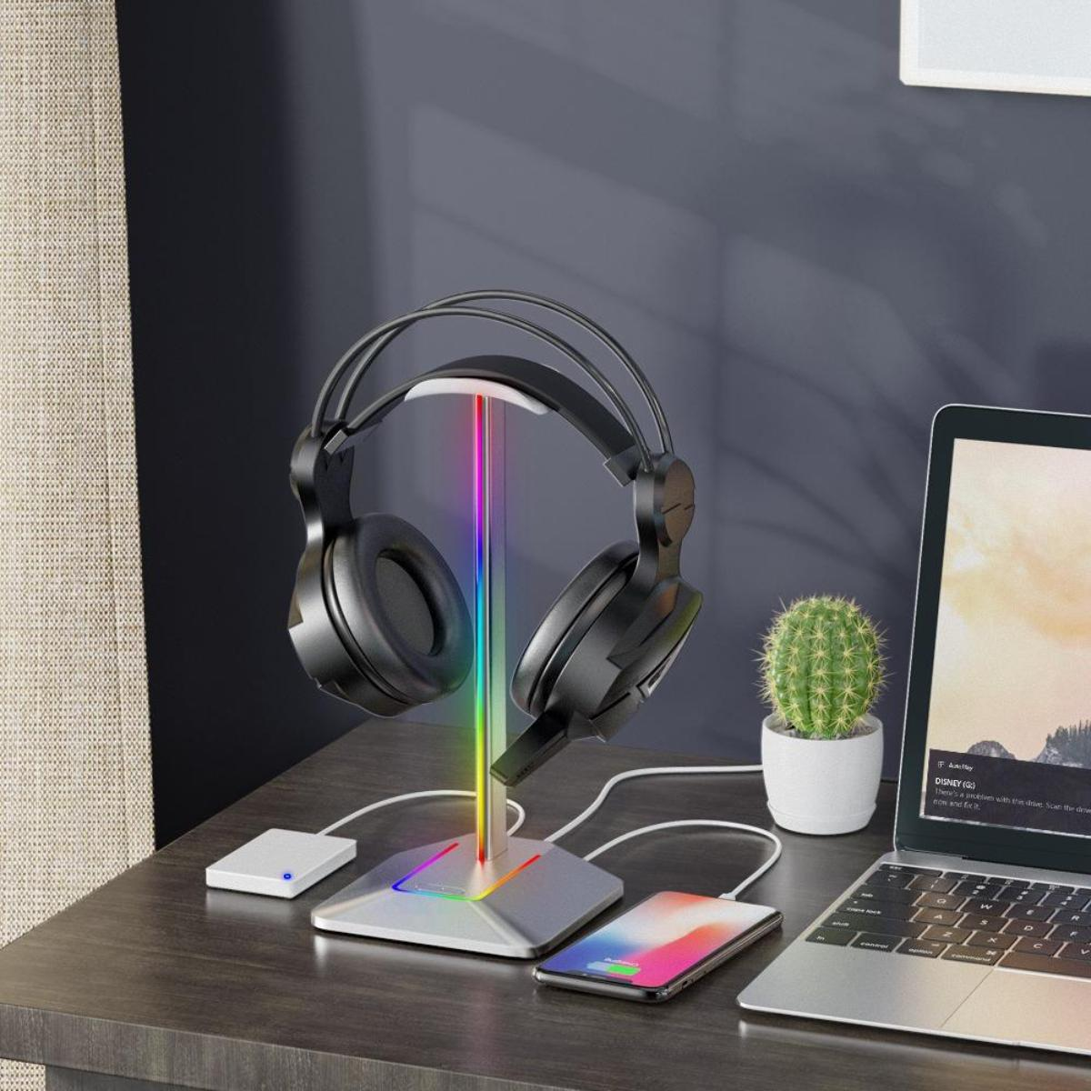 Kopfhörer auf einem Ständer mit LED-Leuchten, Laptop, Telefon und Kaktus auf einem Schreibtisch.