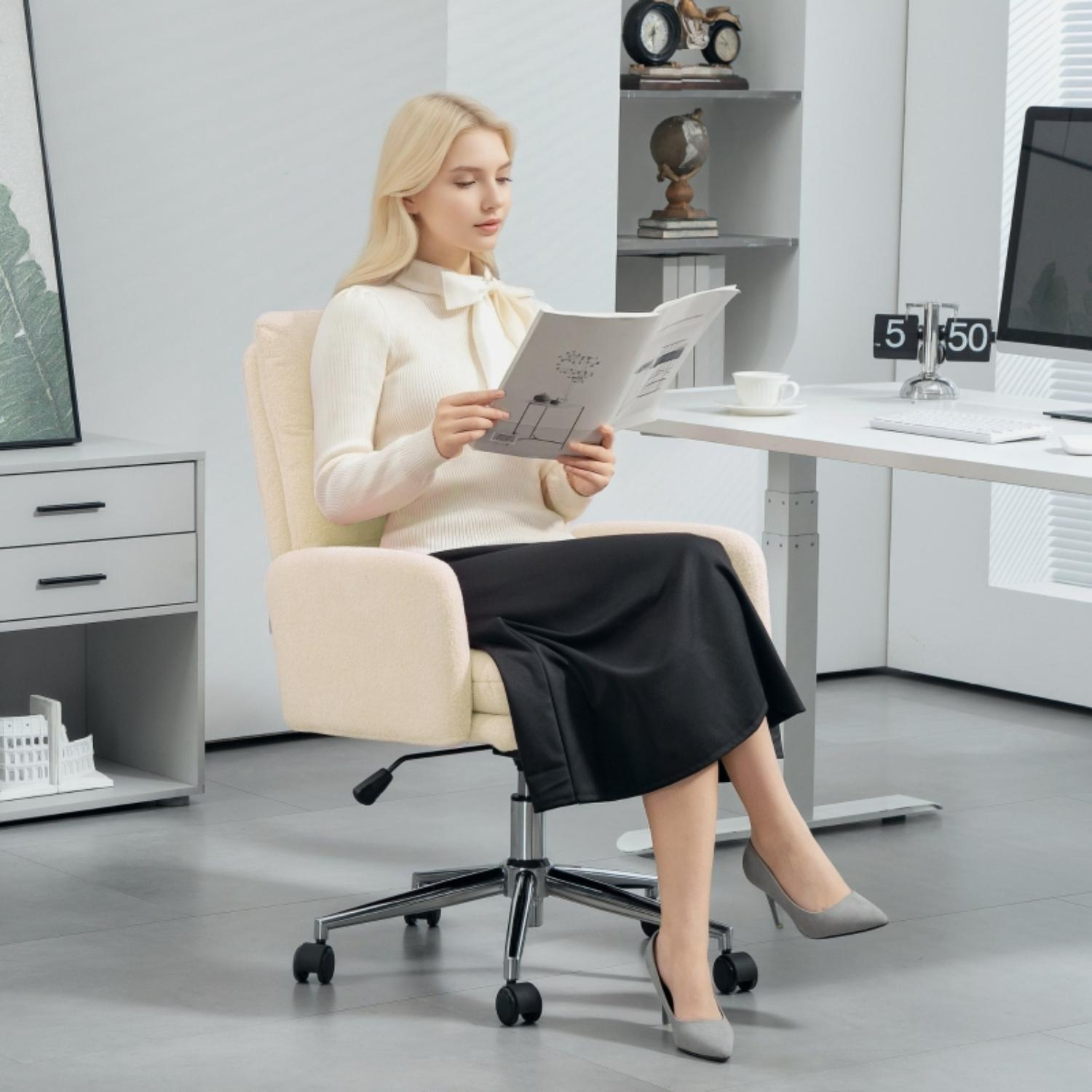 Eine Frau sitzt in einem cremefarbenen Bürostuhl und liest eine Zeitschrift in einer modernen Büroumgebung.