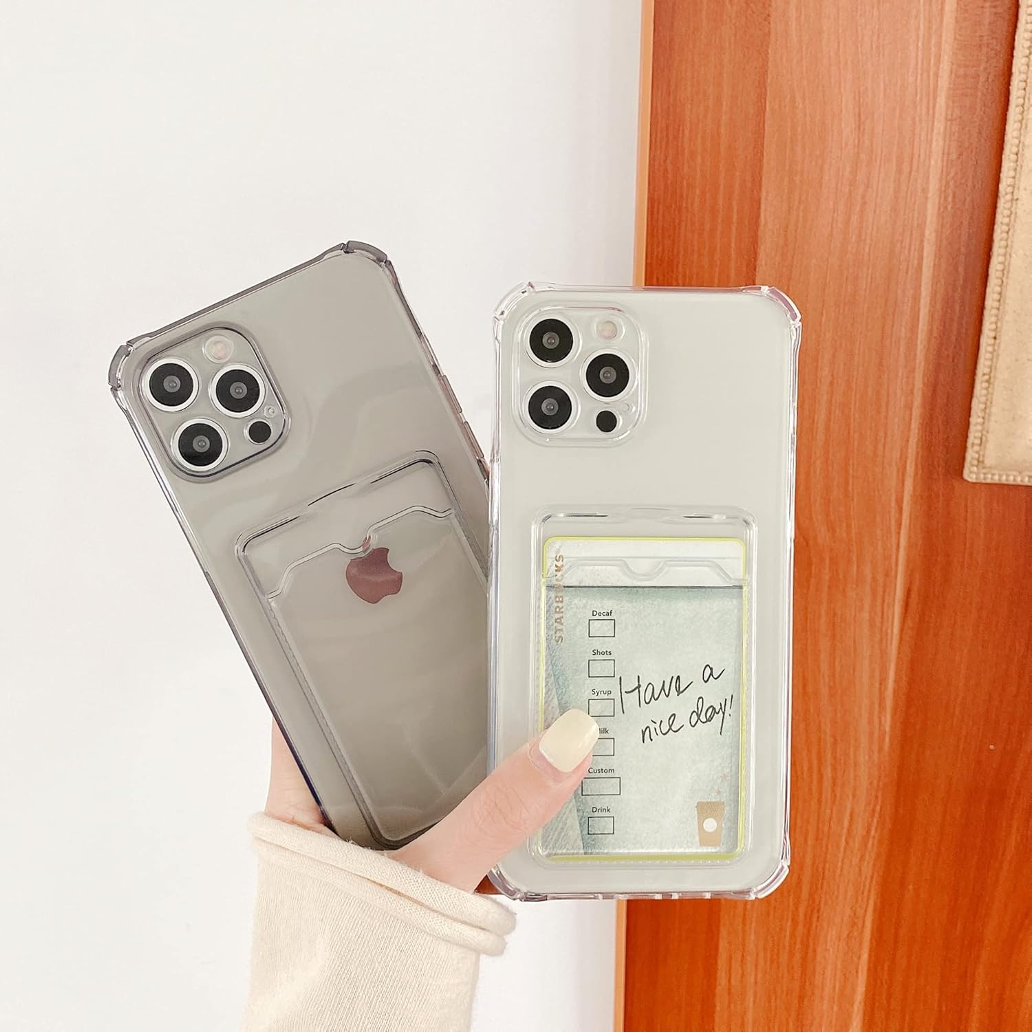 Zwei transparente Handyhüllen mit Kartenhaltern, eine in der Hand gehalten, neben einer Holzwand.