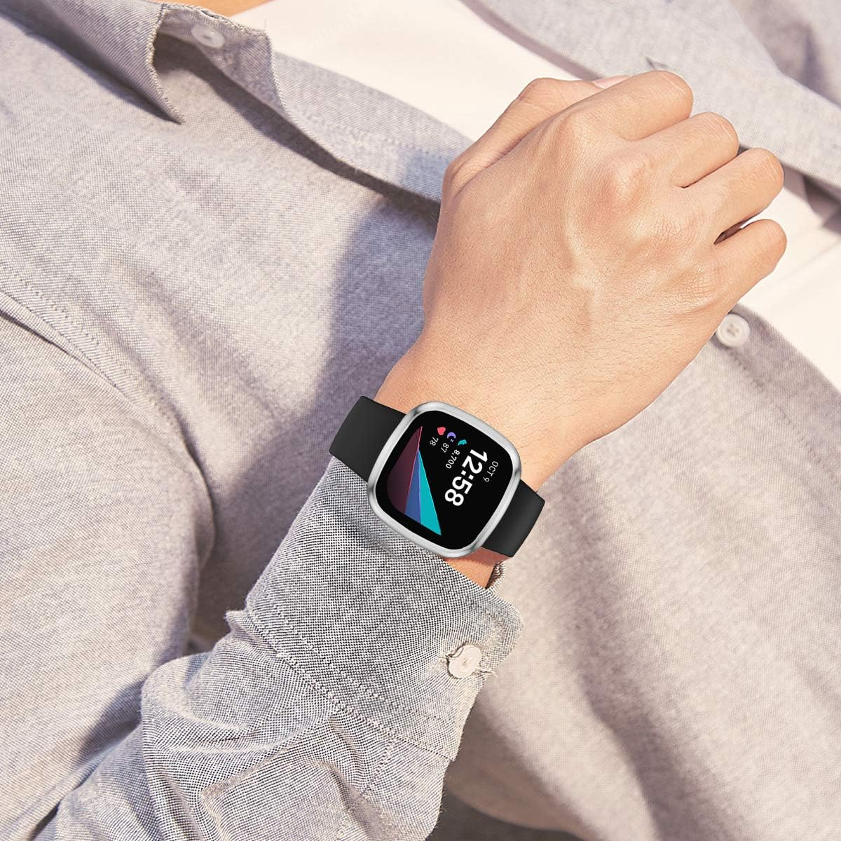Smartwatch mit grauem Gehäuse und schwarzem Armband am Handgelenk einer Person, die einen grauen Anzug trägt.