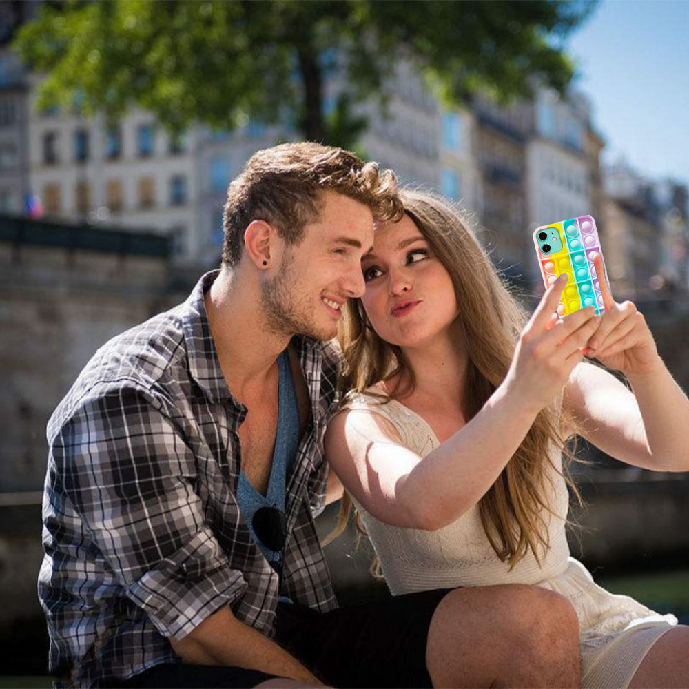 Ein Paar macht ein Selfie. Die Frau hält ein Telefon mit einer bunten, Blasen-Hülle.