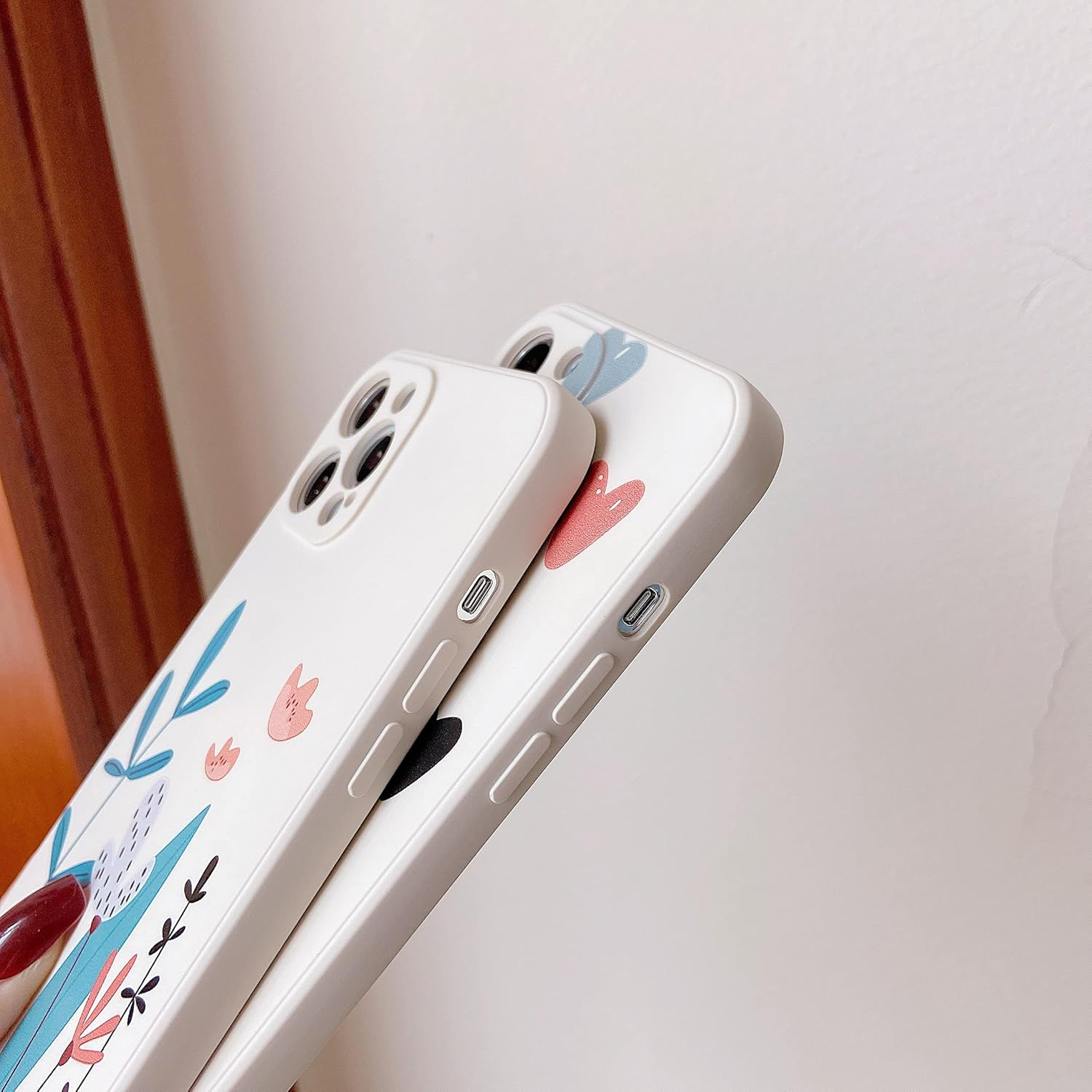 Zwei Handyhüllen mit floralen Designs. Die Hüllen sind weiß.
