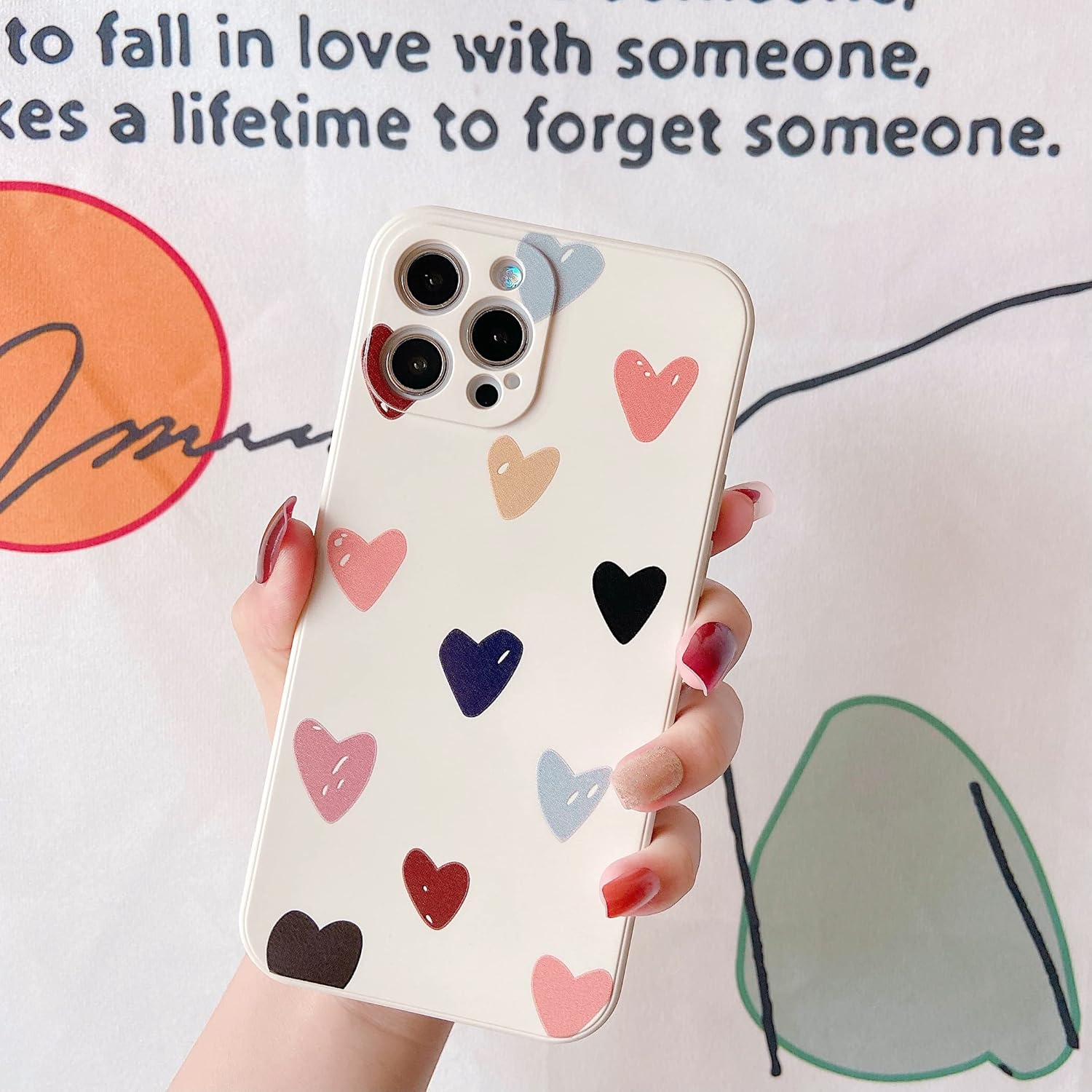 Eine Handyhülle mit Herzdesigns wird in einer Hand gehalten. Die Hülle ist weiß.