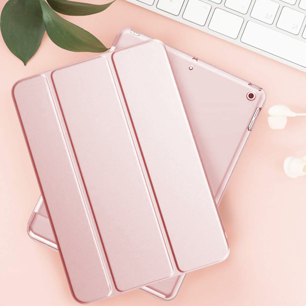 iPad-Hülle und Tastatur. Eine pinke iPad-Hülle liegt auf einer pinken Oberfläche neben einer weißen Tastatur.
