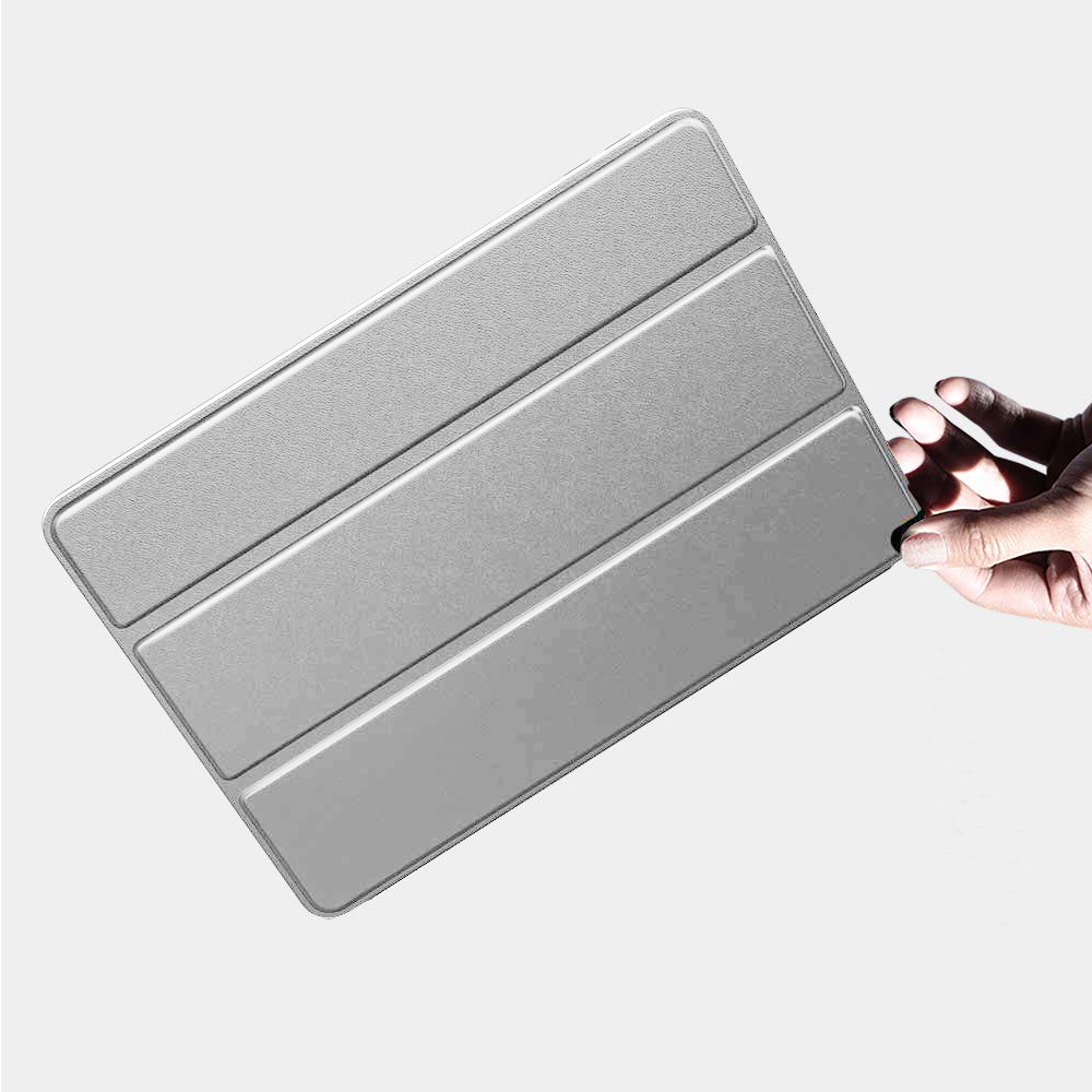 Eine Hand hält eine graue dreifach gefaltete Tablet-Hülle in einer hellen, minimalistischen Umgebung.