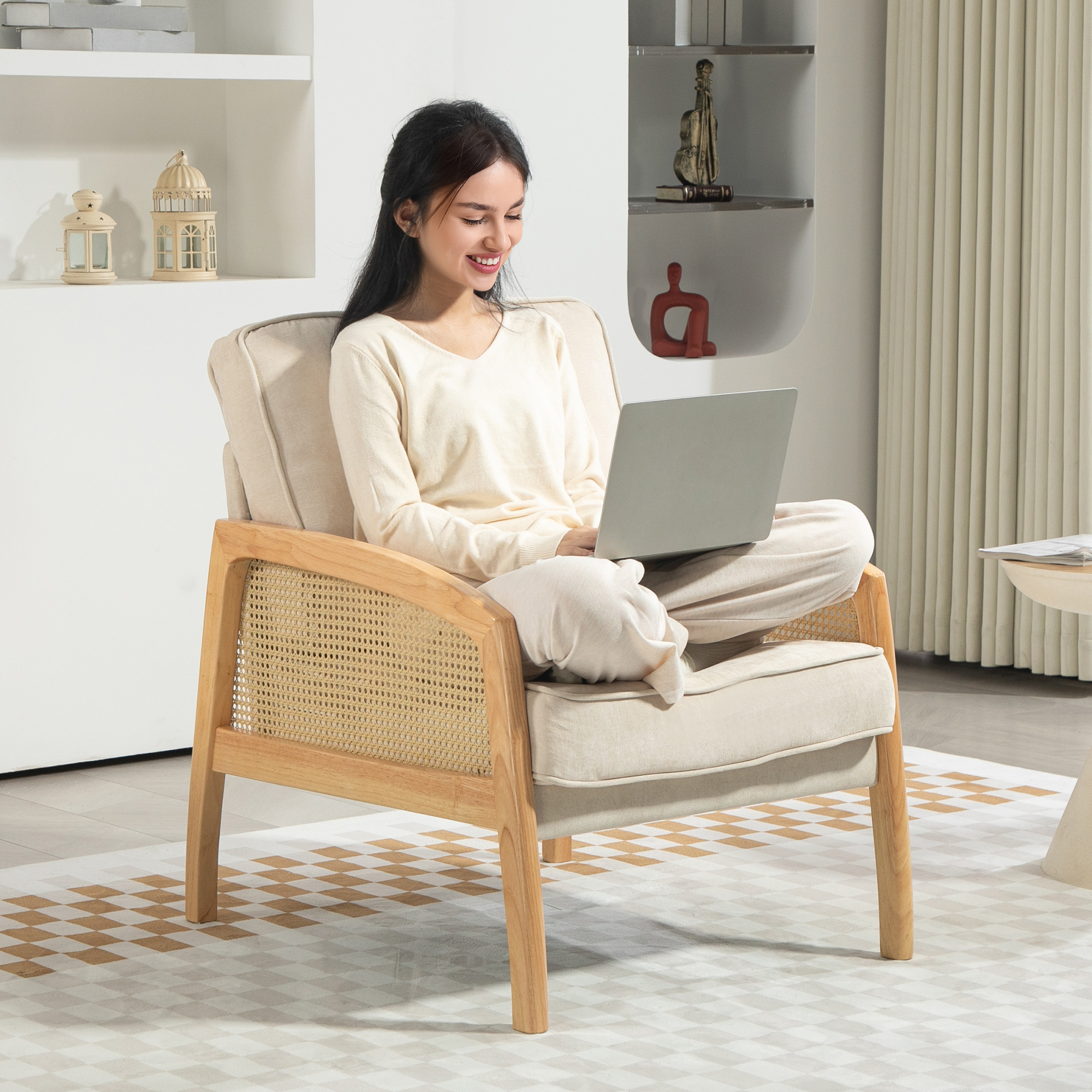 Una mujer se sienta en una silla de madera y mimbre, usando una computadora portátil, en el interior.
