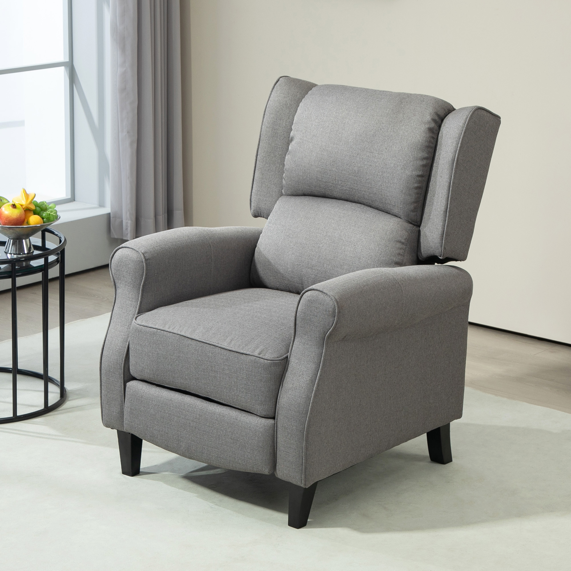 Un sillón reclinable gris con respaldo alto, colocado en un salón, con una mesa auxiliar.