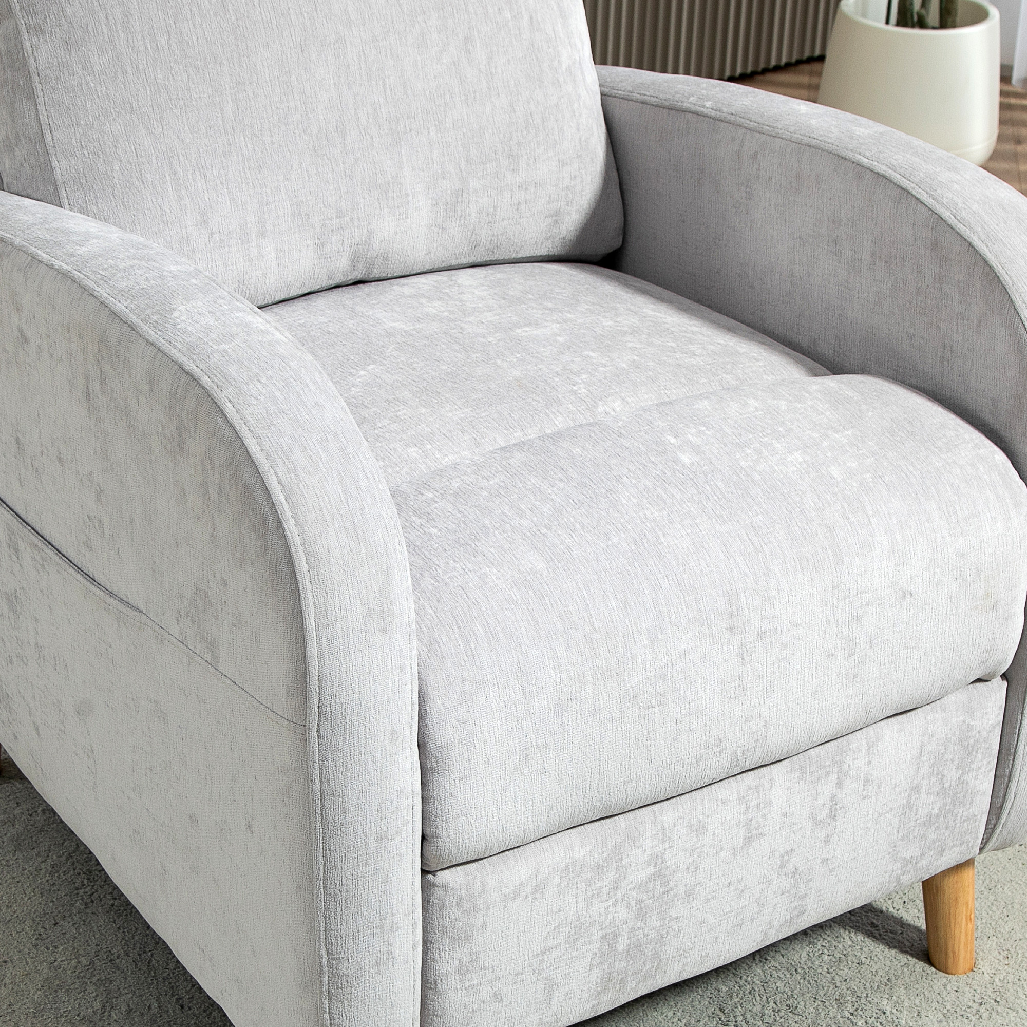Primer plano de un sillón gris claro con un asiento suave y acolchado y reposabrazos redondeados.