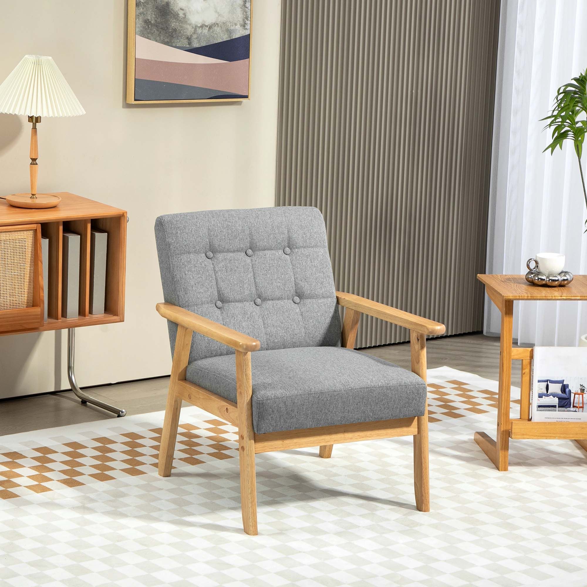 Un sillón tapizado gris con estructura de madera, con una mesa auxiliar y una lámpara, sobre una alfombra estampada.