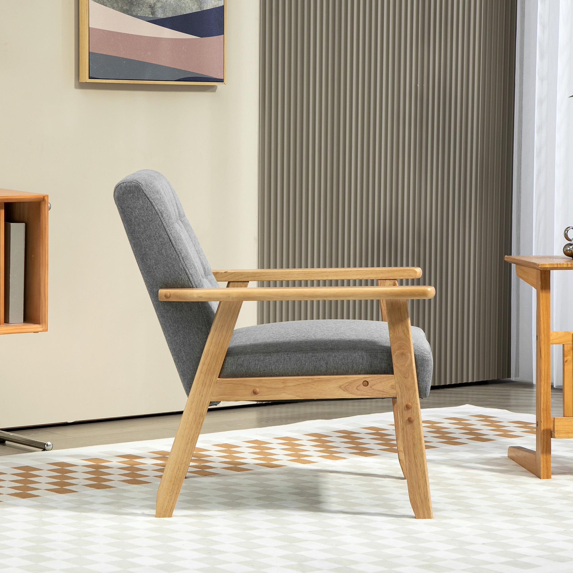 Un sillón gris con reposabrazos y patas de madera se asienta sobre un suelo estampado, junto a una pequeña mesa de madera.