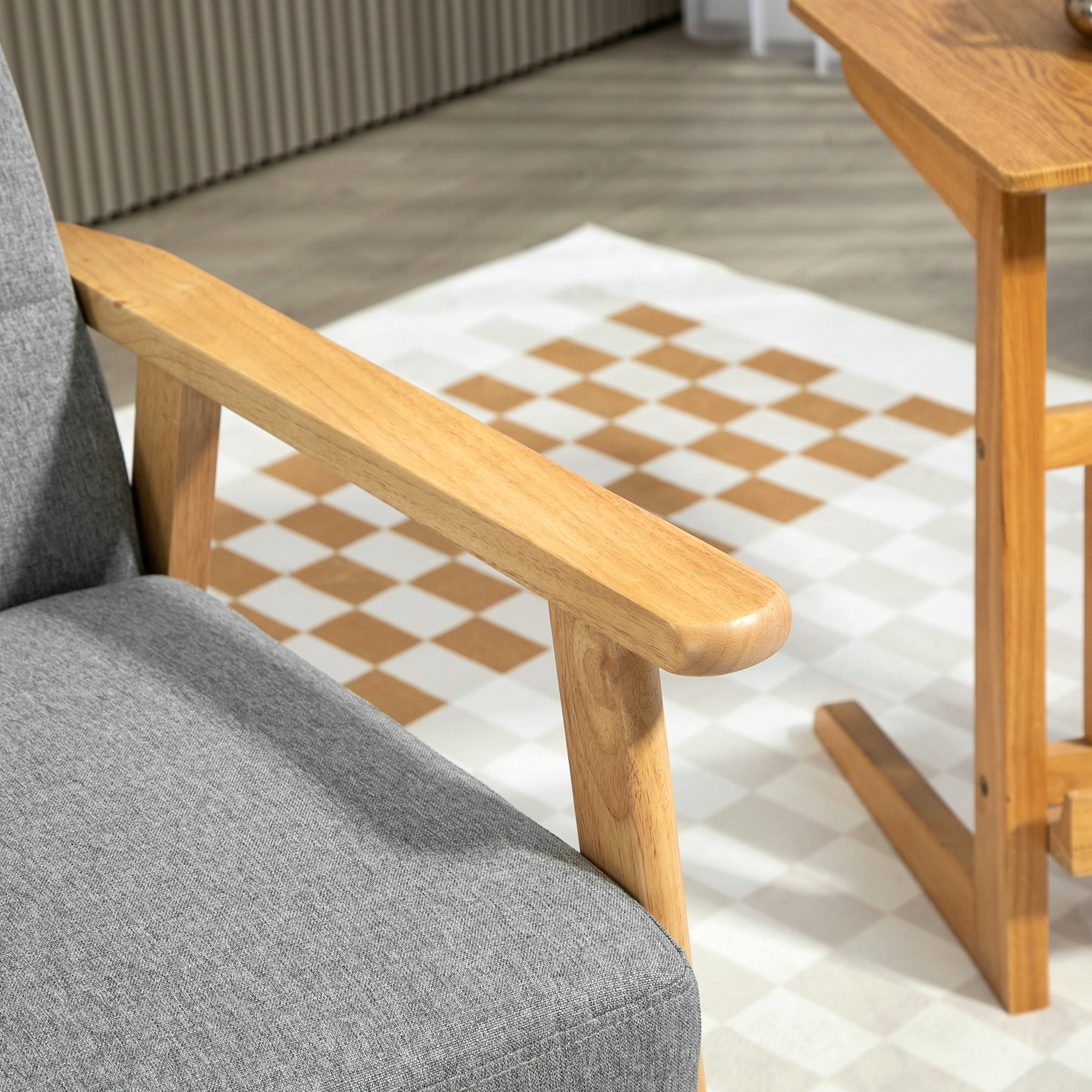 Un sillón gris con reposabrazos de madera se asienta sobre un suelo estampado, junto a una pequeña mesa de madera.