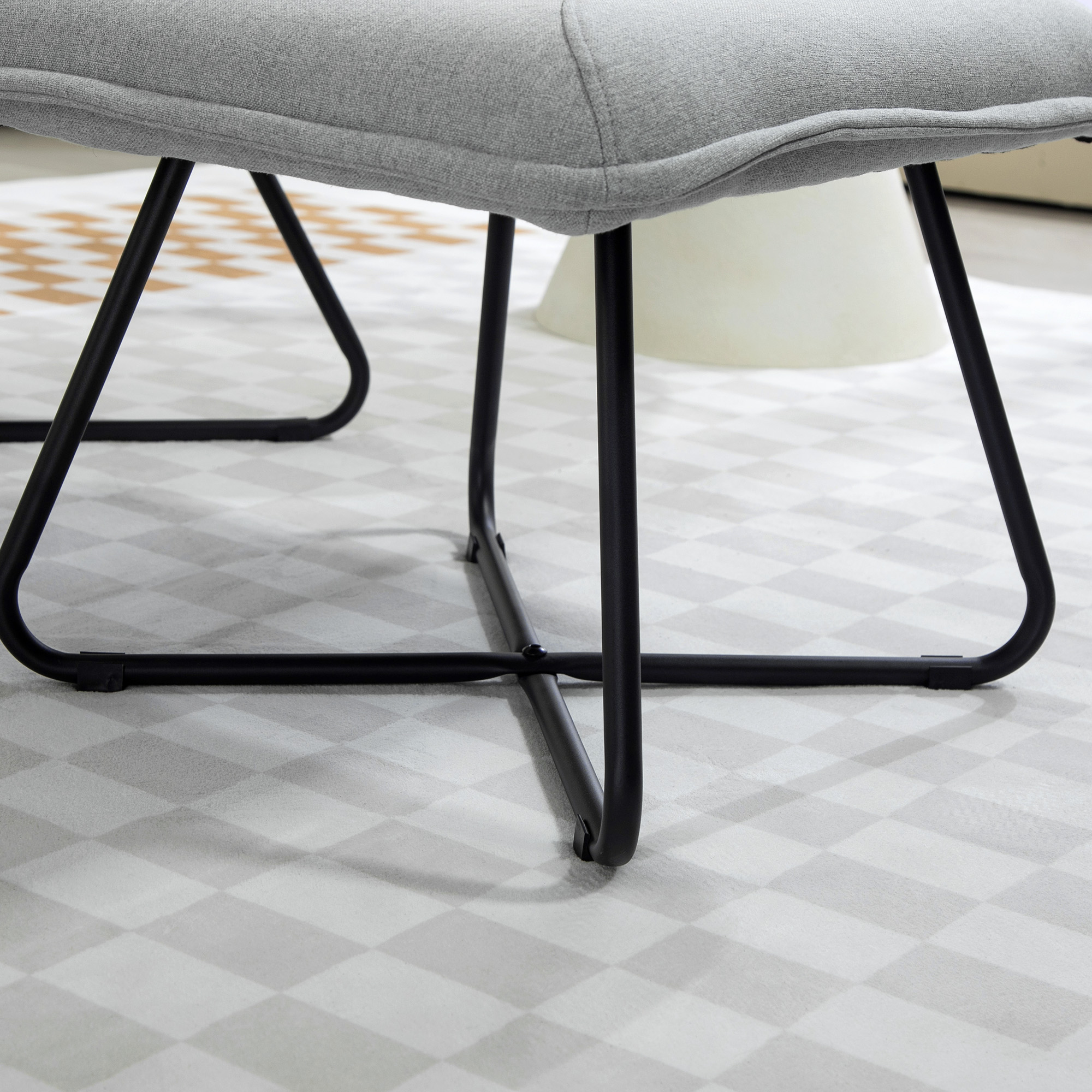 Primer plano de las patas de una silla gris sobre una alfombra estampada, que muestra la construcción y la textura de la tela de la silla.