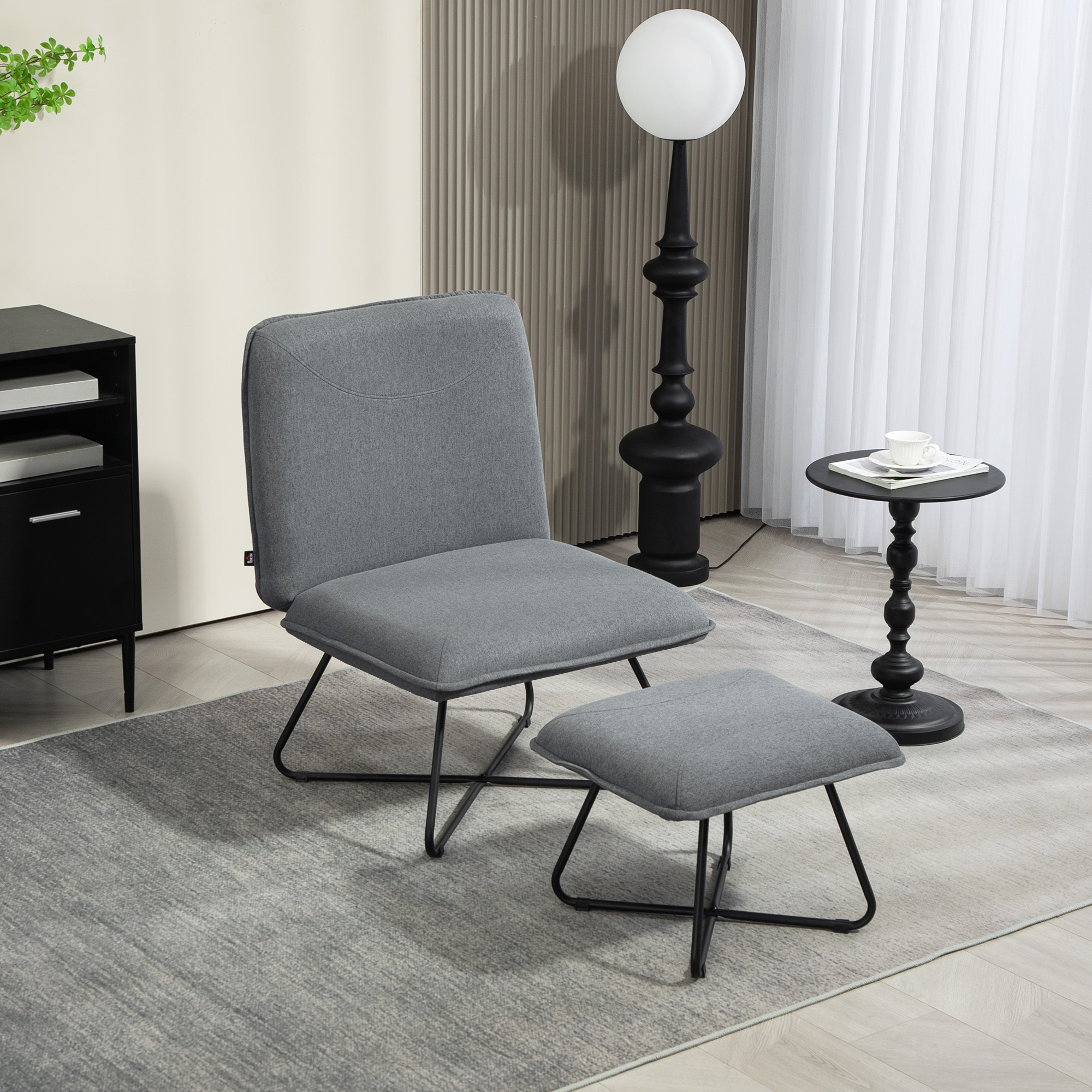 Juego de silla y reposapiés grises, base negra, lámpara, mesa auxiliar.
