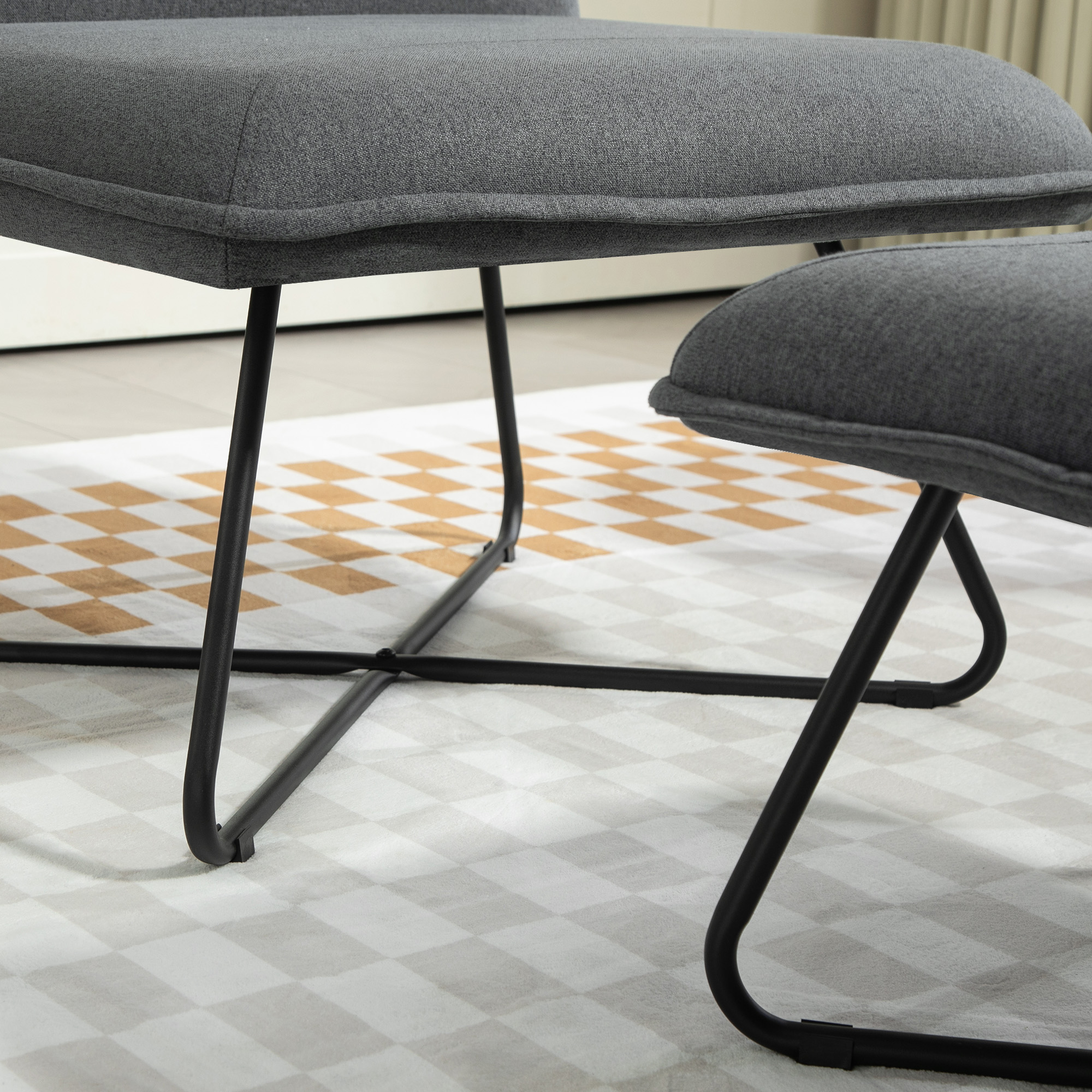 Primer plano de muebles tapizados grises con patas de metal negro sobre una alfombra estampada.