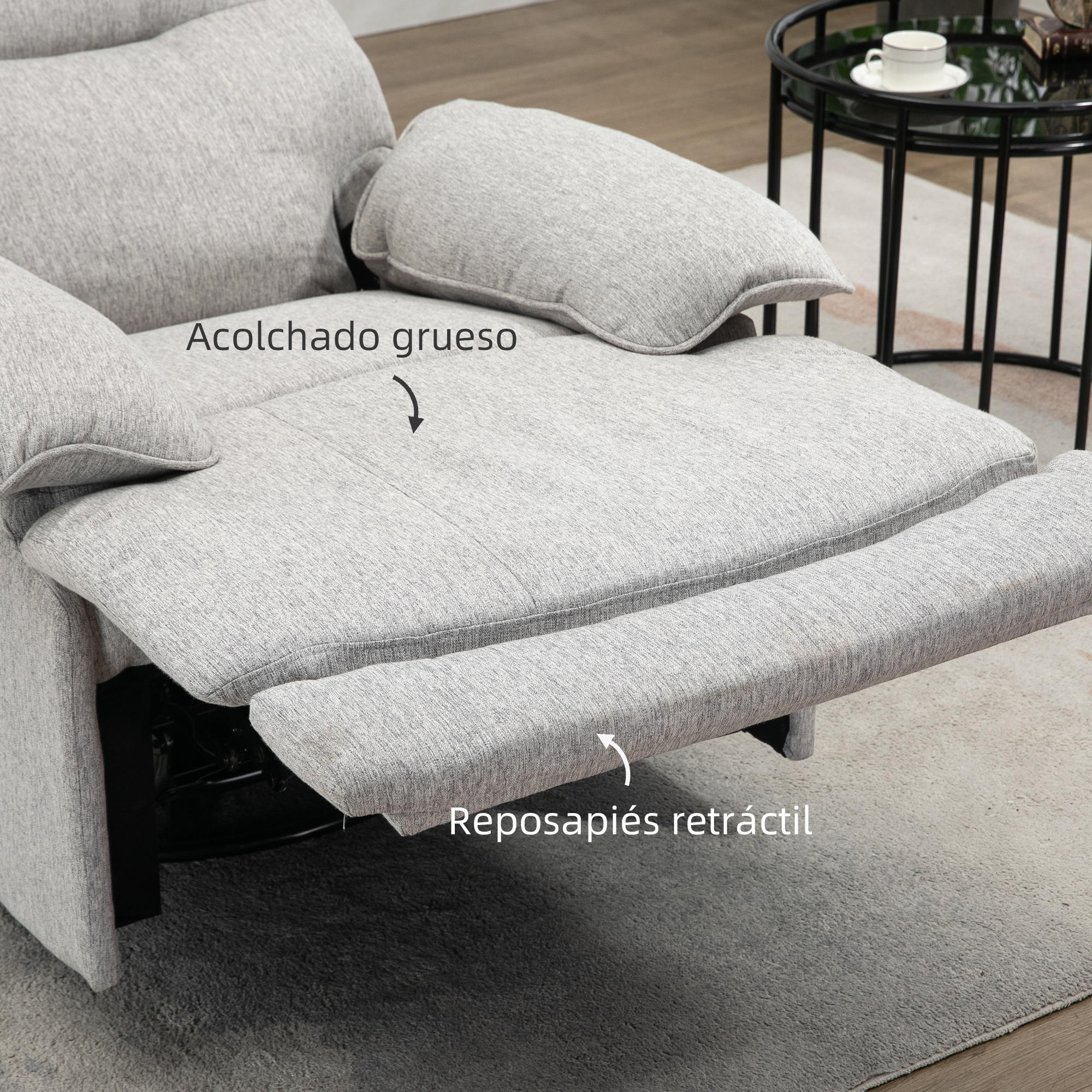 Un sillón reclinable gris cuenta con un acolchado grueso y un reposapiés retráctil, ofreciendo comodidad y soporte.