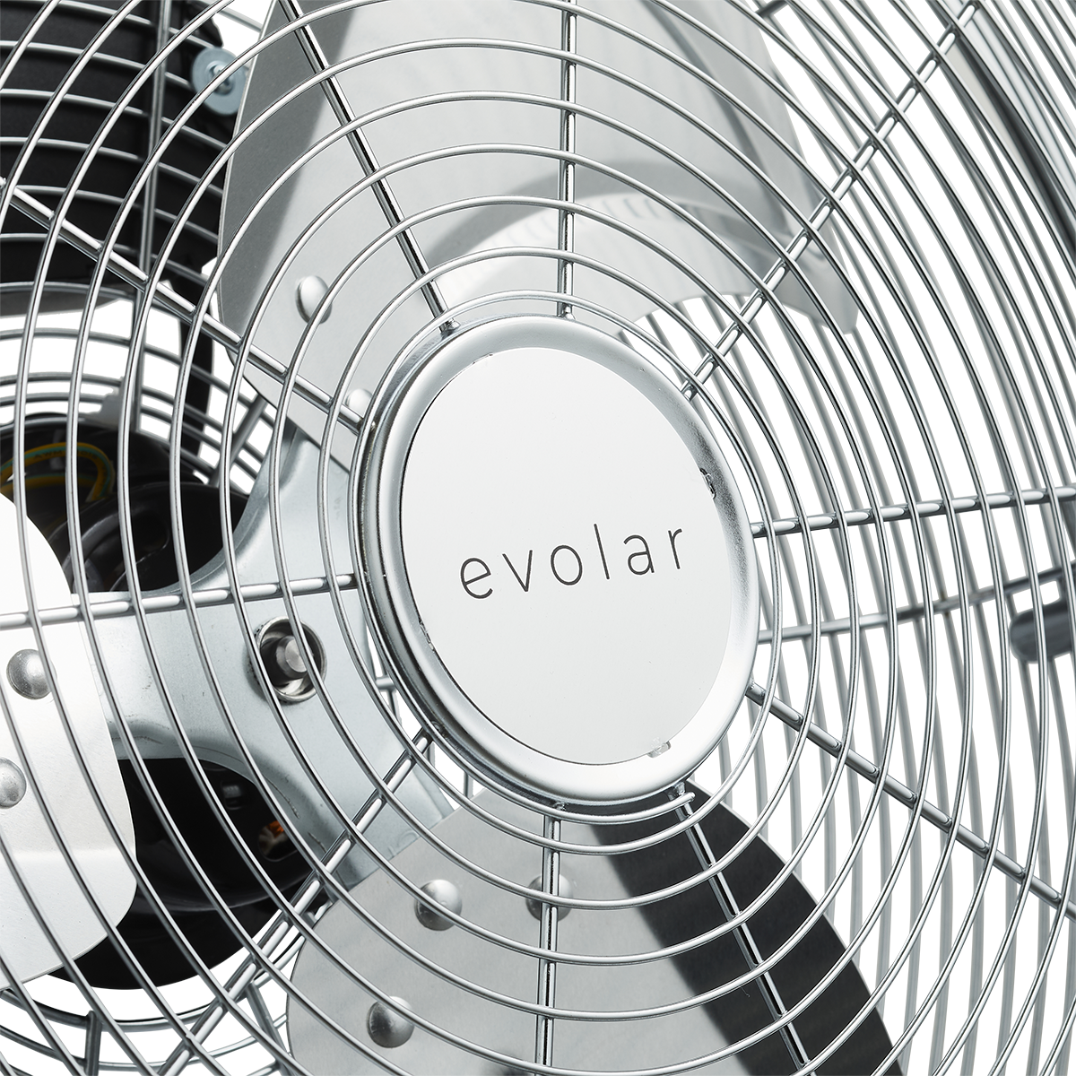 Primo piano di un ventilatore cromato con una gabbia di filo metallico. Il marchio è stampato sopra.