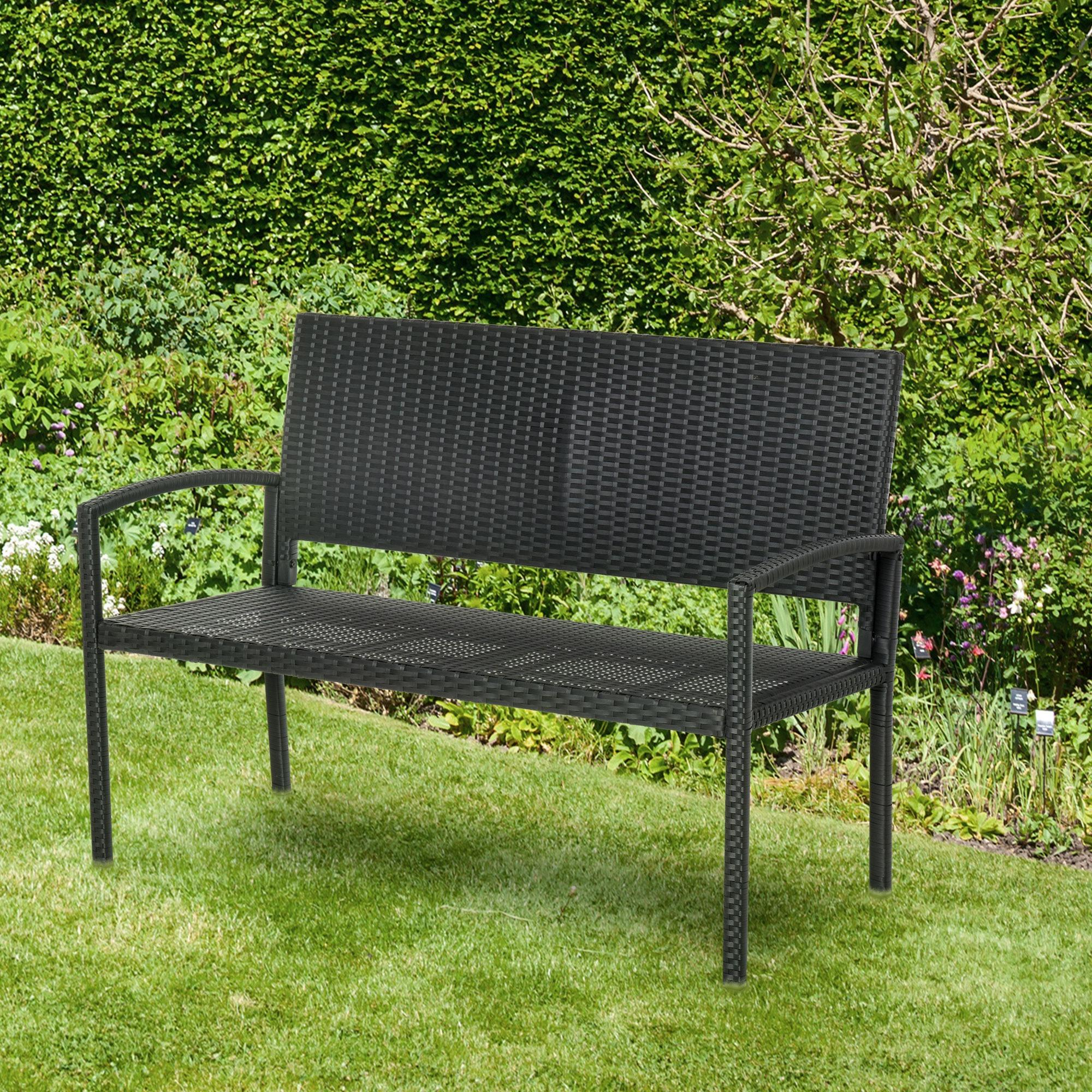 Schwarze Gartenbank aus Korbgeflecht auf dem Rasen in einer Gartenanlage.