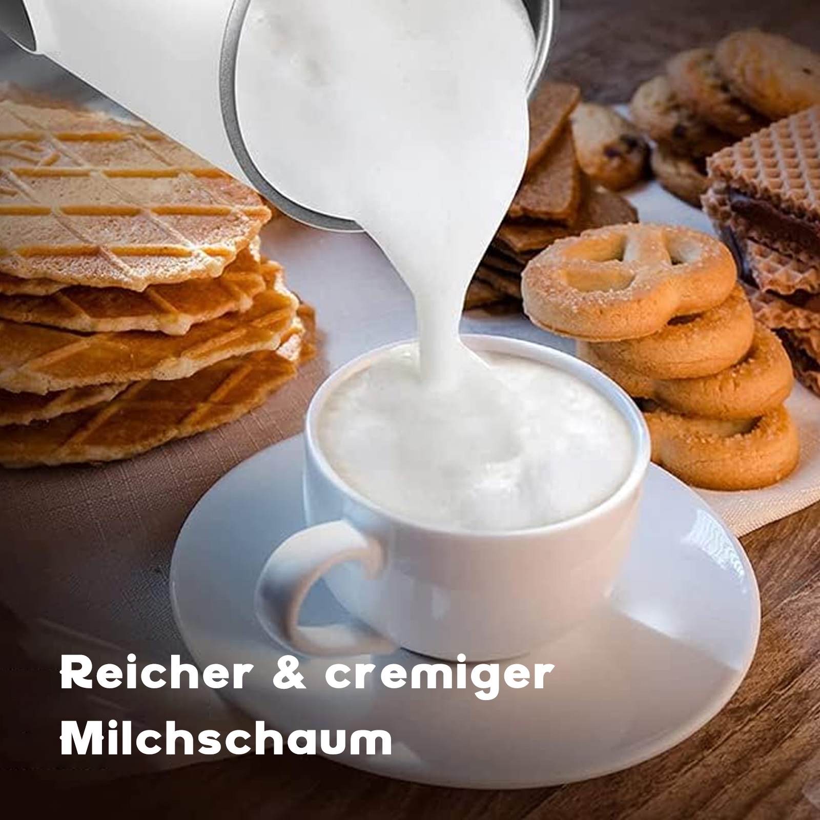 Milch wird in eine Tasse Schaum gegossen, mit Keksen und Waffeln im Hintergrund.