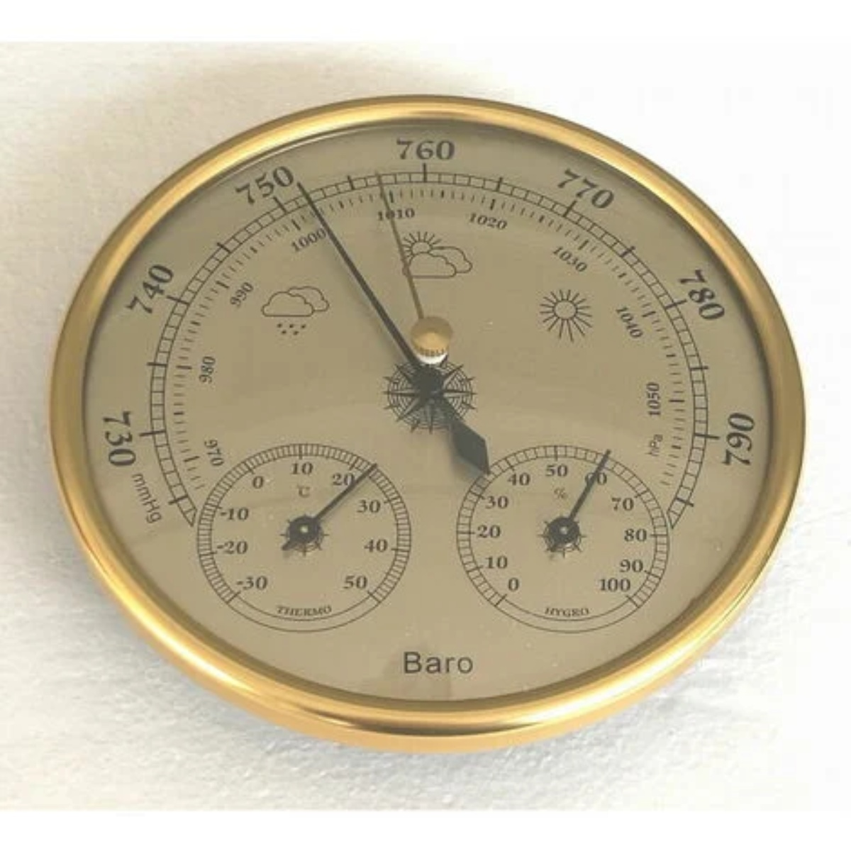 Ein runder, analoger Barometer mit Goldrahmen, der Temperatur-, Feuchtigkeits- und Druckmesswerte anzeigt.