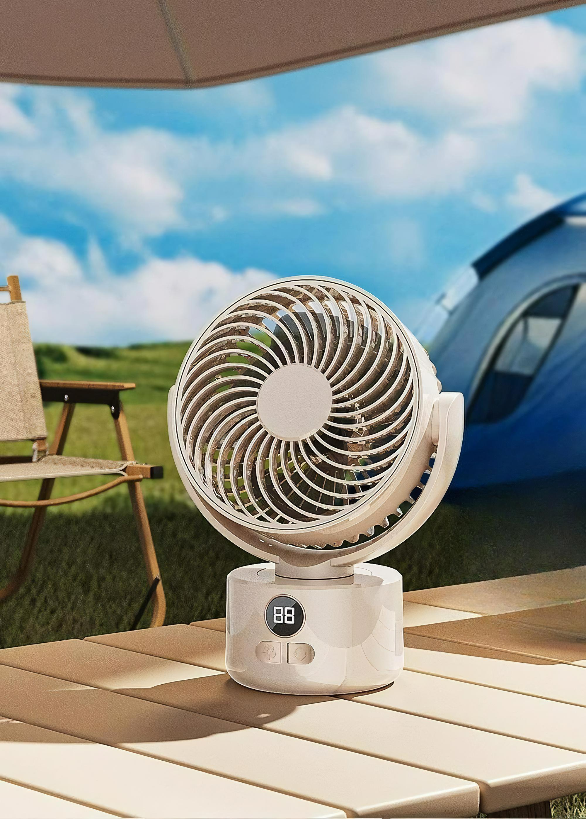 Ein weiß-goldener Ventilator auf einem Holzdeck. Ein Zelt, Stuhl und Sonnenschirm sind sichtbar.