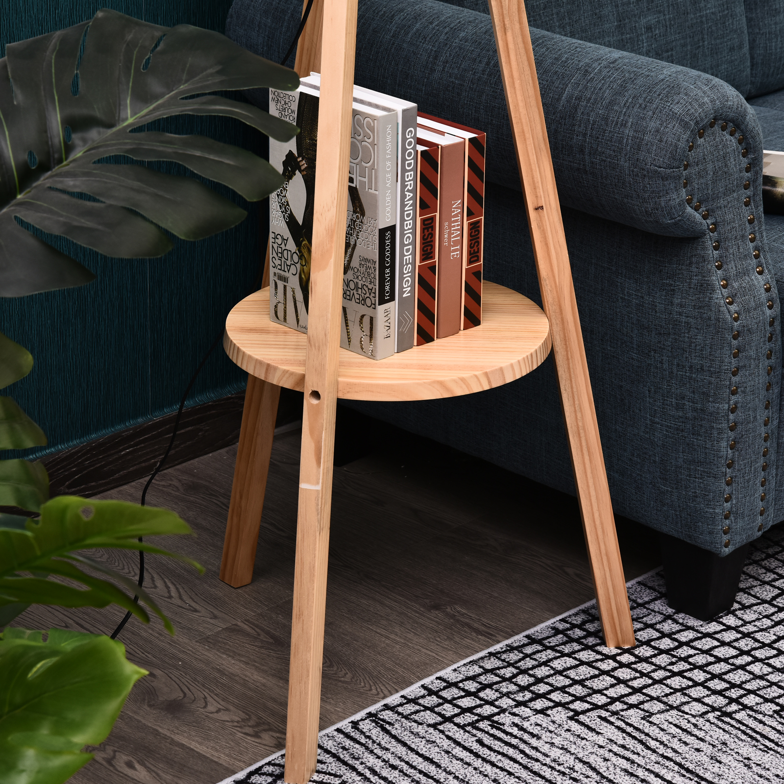 Vista de cerca de libros en un estante integrado en una lámpara trípode de madera, con sofá azul al fondo.