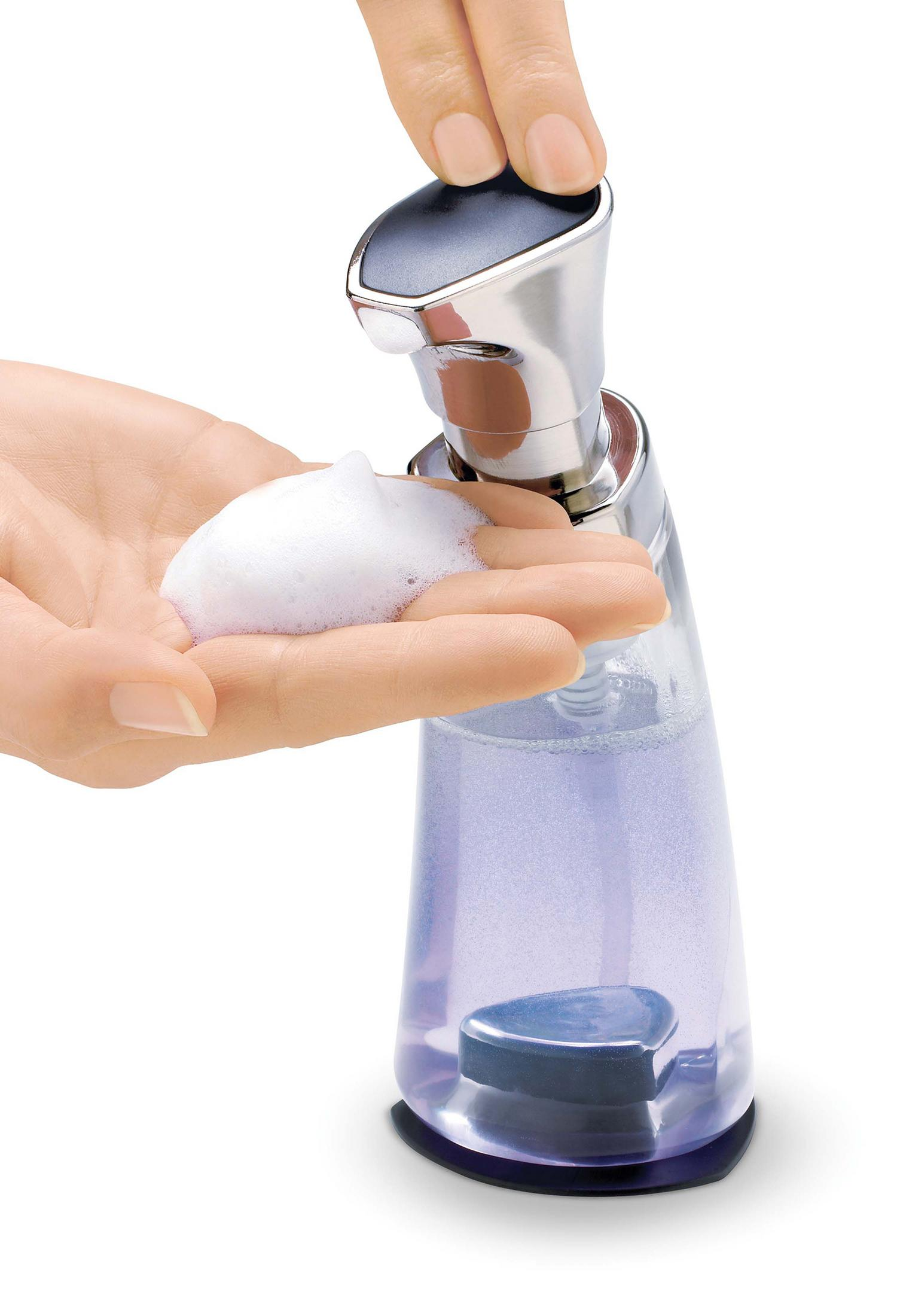 Eine Hand gibt schäumende Seife aus einer durchsichtigen Flasche mit silberner Pumpe über eine Hand ab.