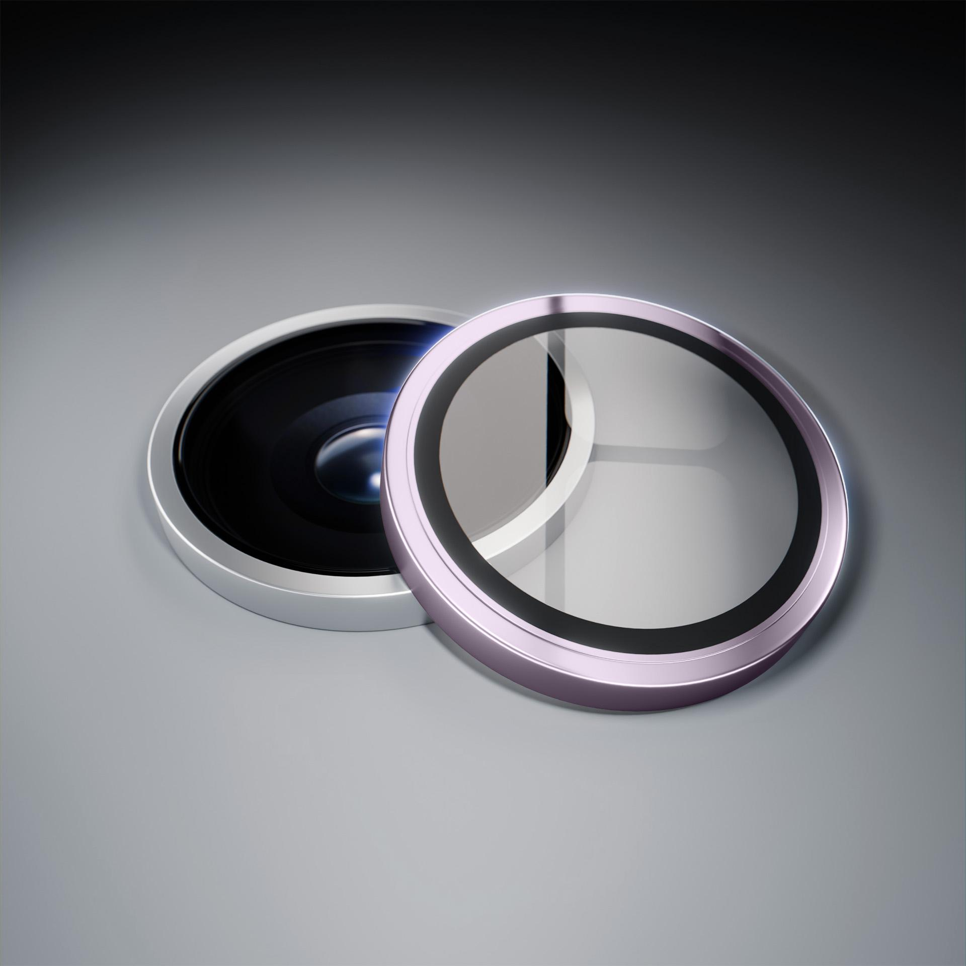 Zbliżenie dwóch okrągłych obiektywów aparatu z srebrnymi i różowymi obwódkami na szarej powierzchni.