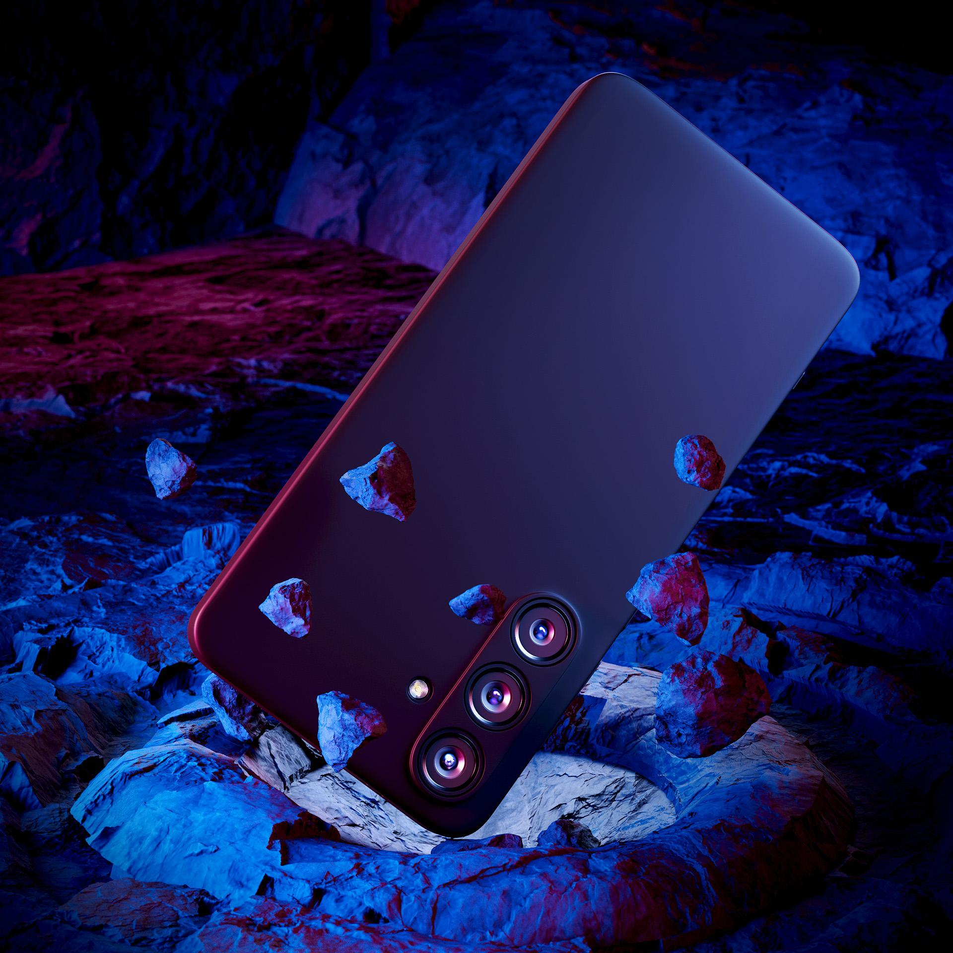 Ciemny smartfon z trzema obiektywami jest wyśrodkowany na niebiesko-czerwonej powierzchni skały.