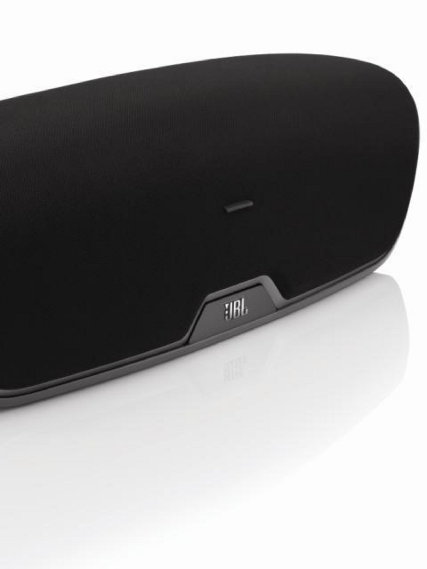 Resimde, beyaz bir arka plan üzerinde, şık bir tasarıma ve önünde JBL logosuna sahip siyah bir JBL hoparlörü görülmektedir.