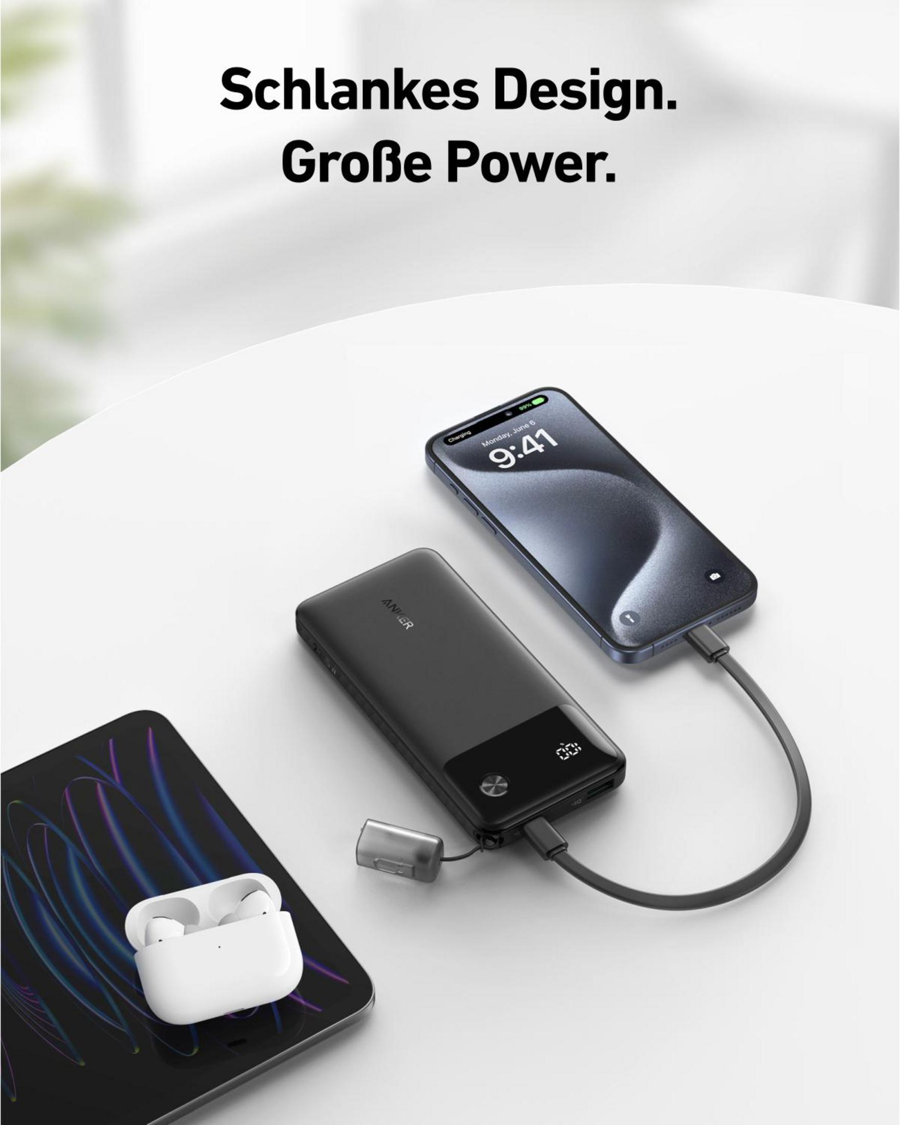 Un power bank nero carica un telefono e un tablet, con AirPods visibili su un tavolo bianco.