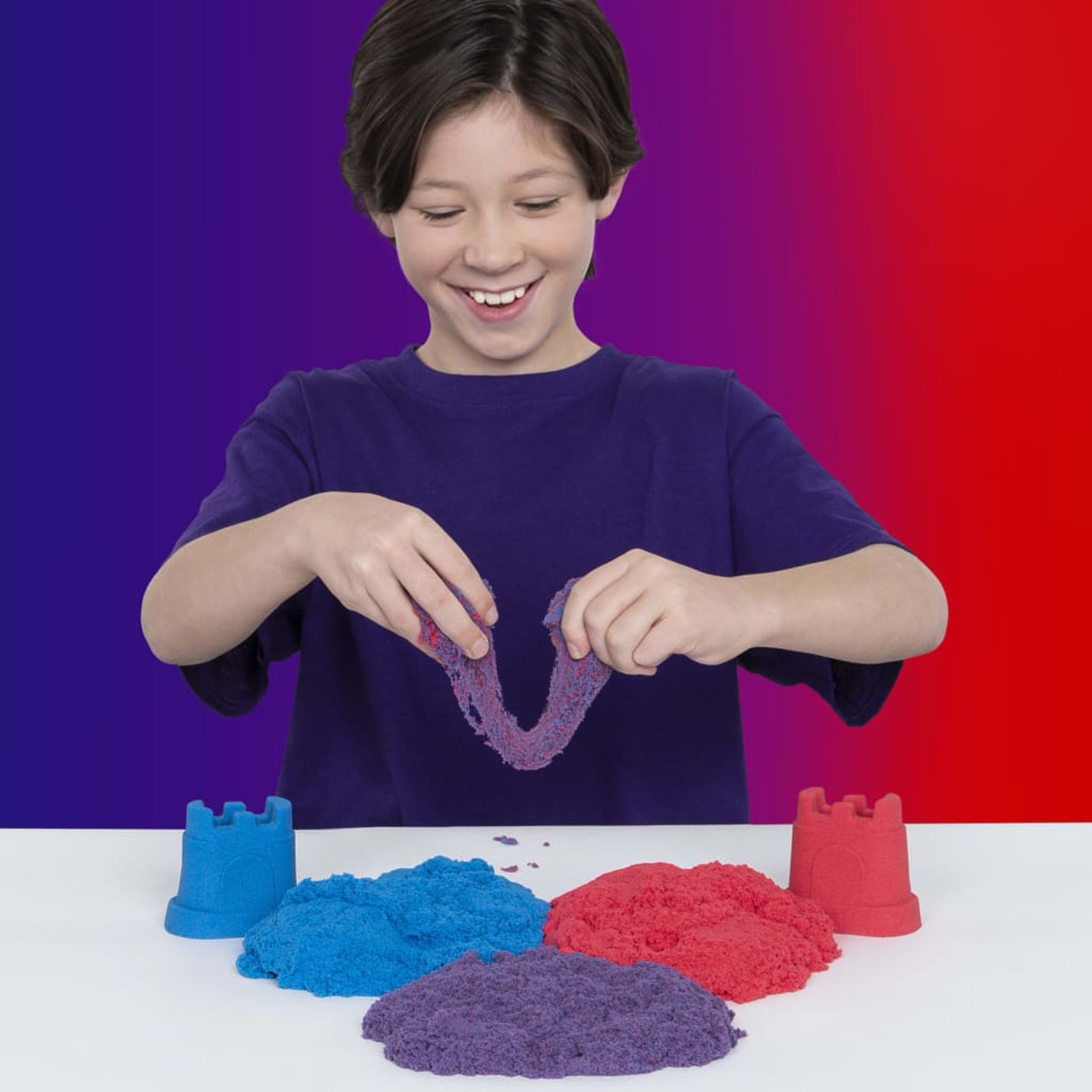 Un garçon joue avec Kinetic Sand, créant des formes et s'amusant.