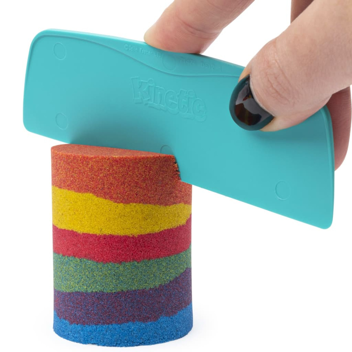 Une main lisse le sable Kinetic arc-en-ciel avec un outil bleu.